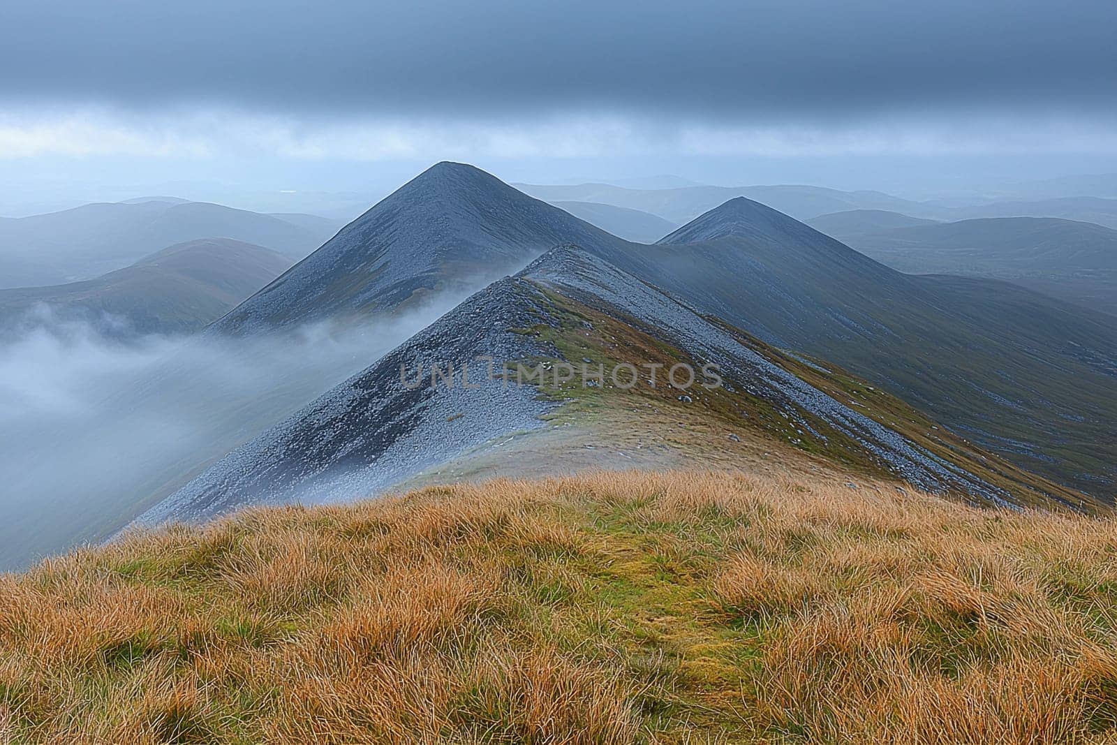 Misty mountains rise dramatically against a gray sky in a tranquil natural setting.