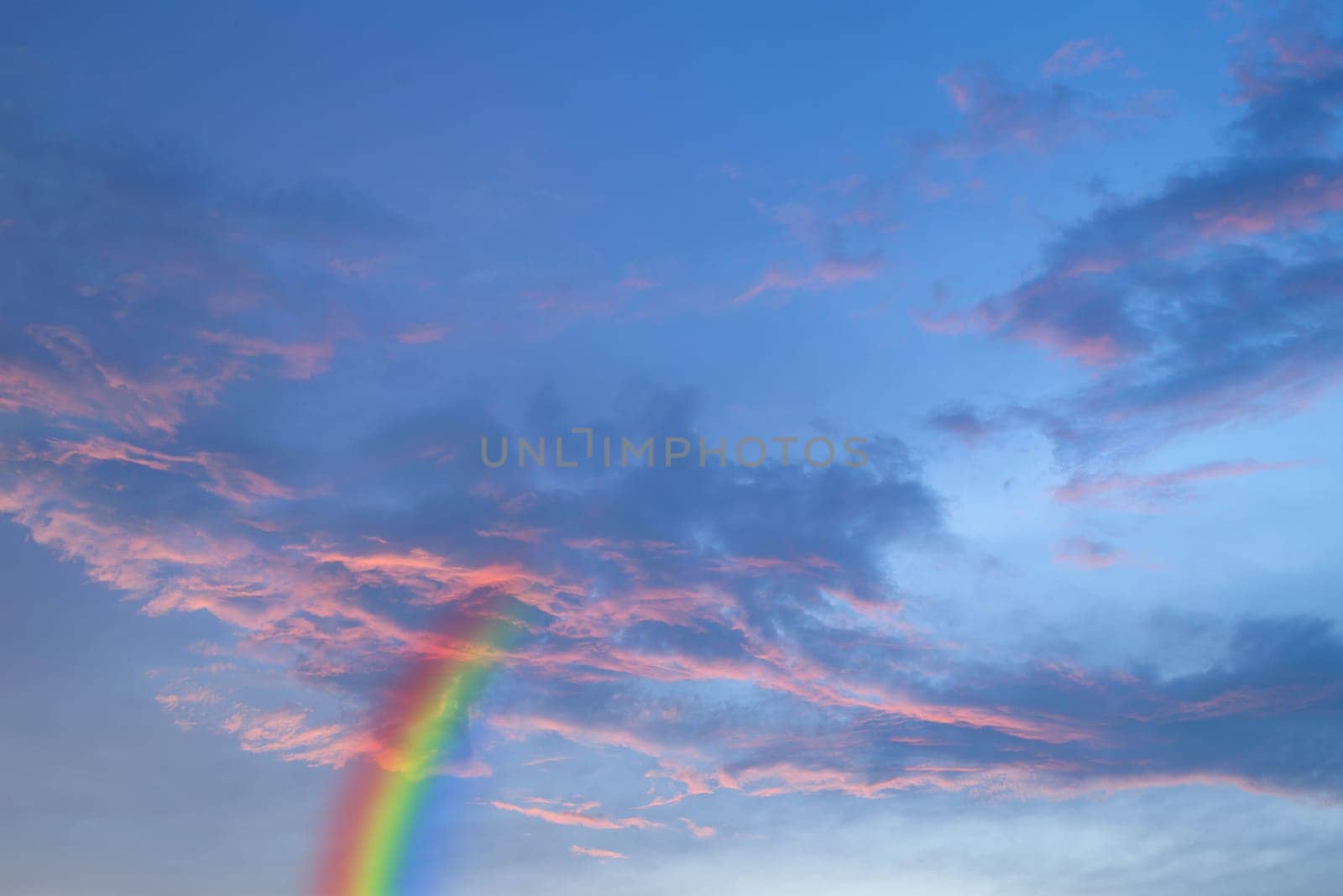 Nature cloudscape with red sky and storm cloud with rainbow