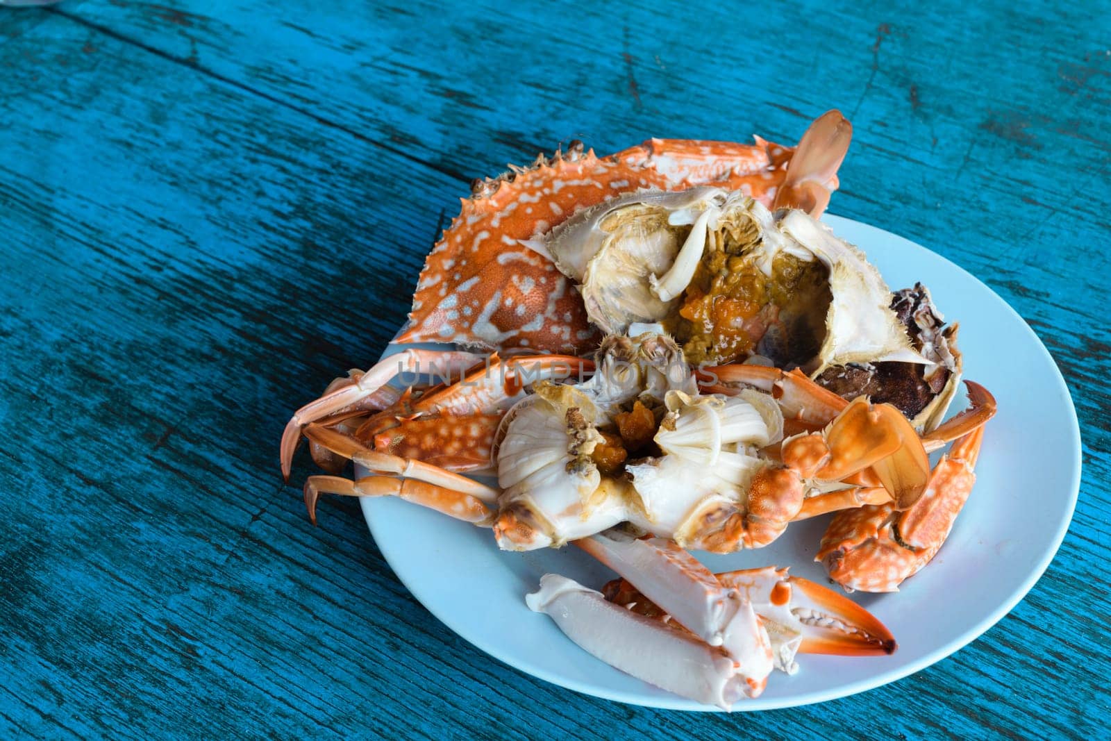Steamed crab in dish on blue wood table
