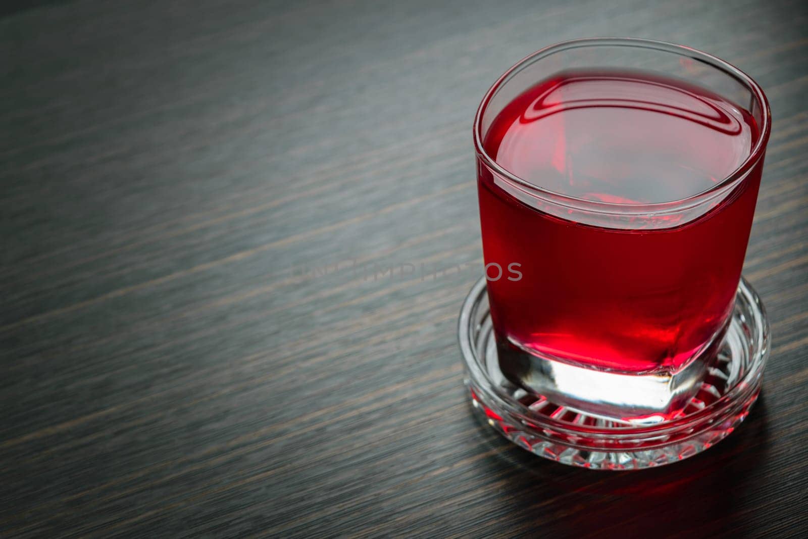 Sweet red water drink in glass on wood table