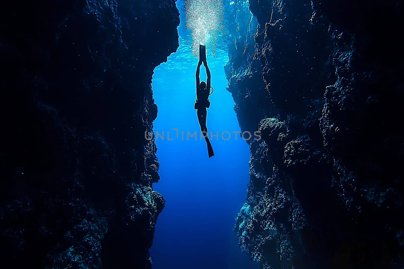 A diver gracefully swims through a narrow underwater canyon surrounded by vibrant marine life and clear blue water.