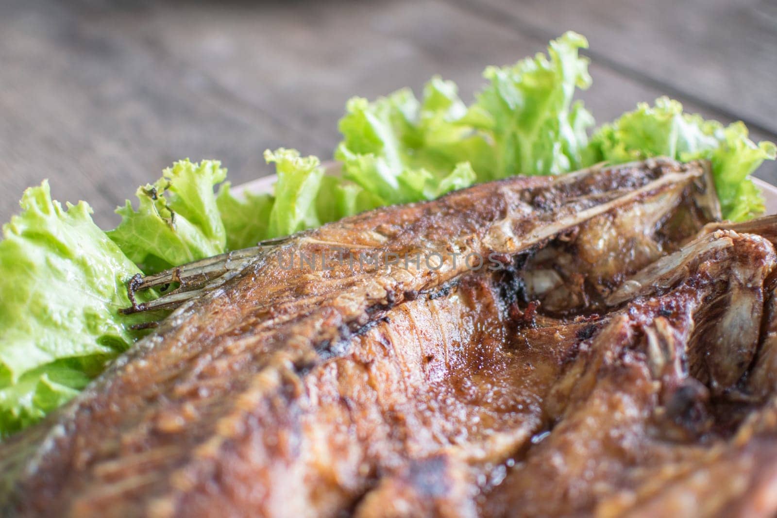 Fish fried fish sauce on green vegetable on wood table