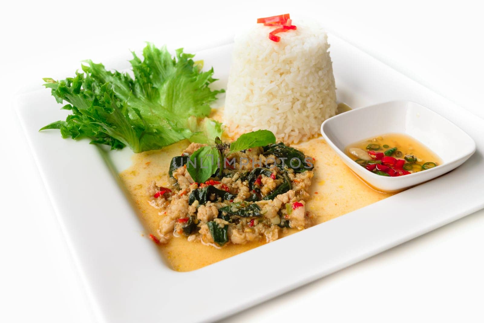 Rice topped with stir-fried pork and basil isolated on white background