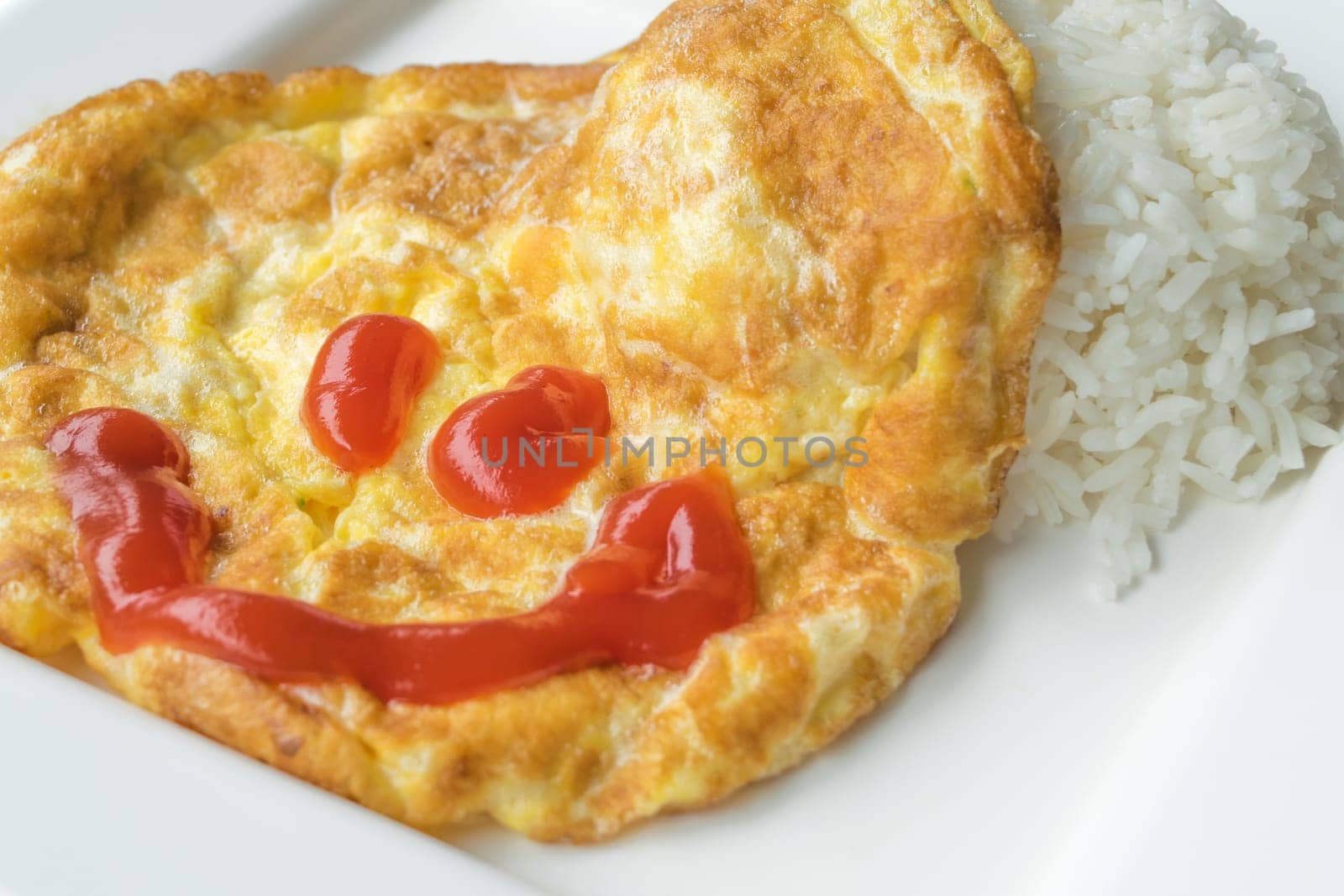Omelet rice in white dish with smiling chilli sauce. isolated on white background.