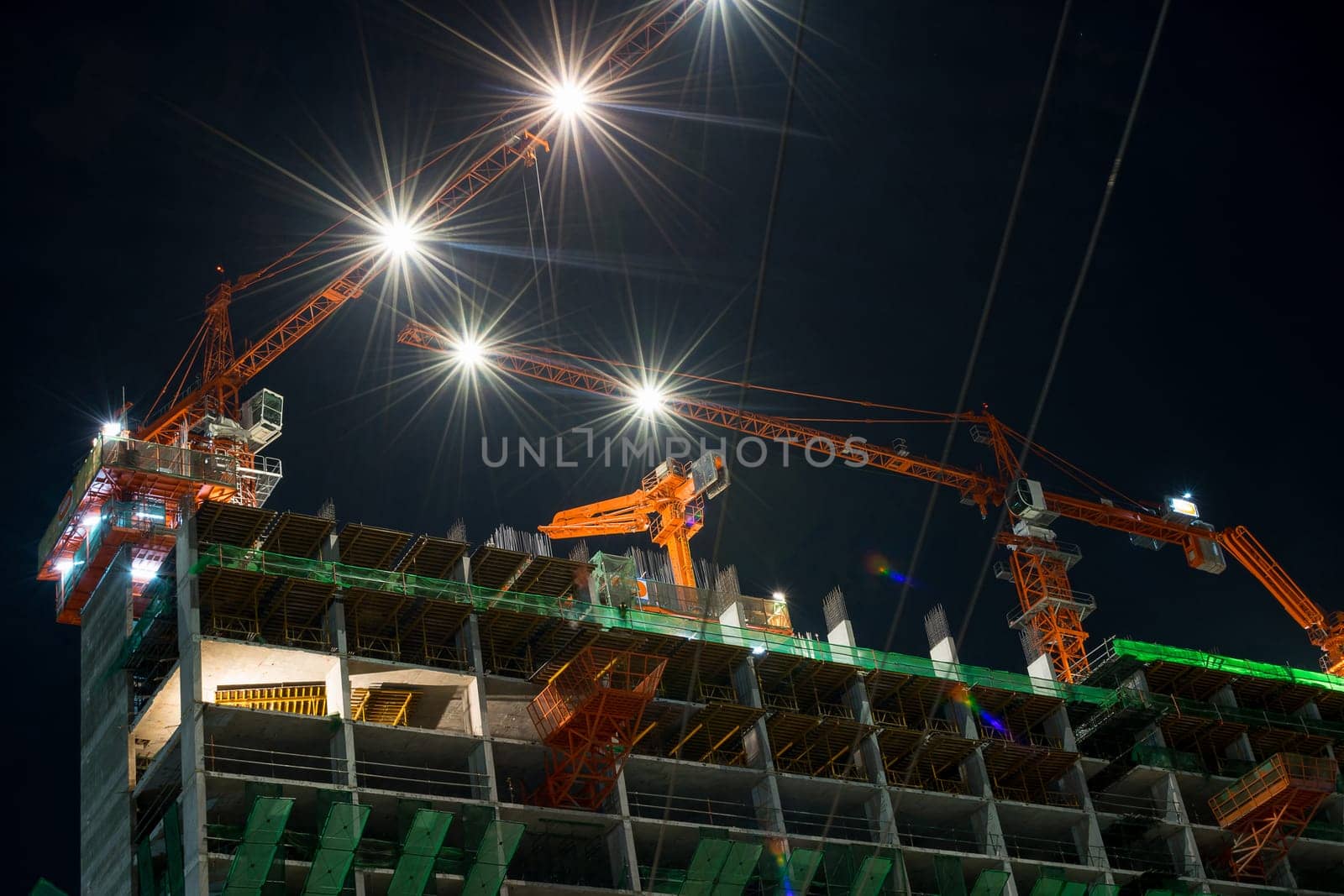Nighttime and crane working with building construction in city