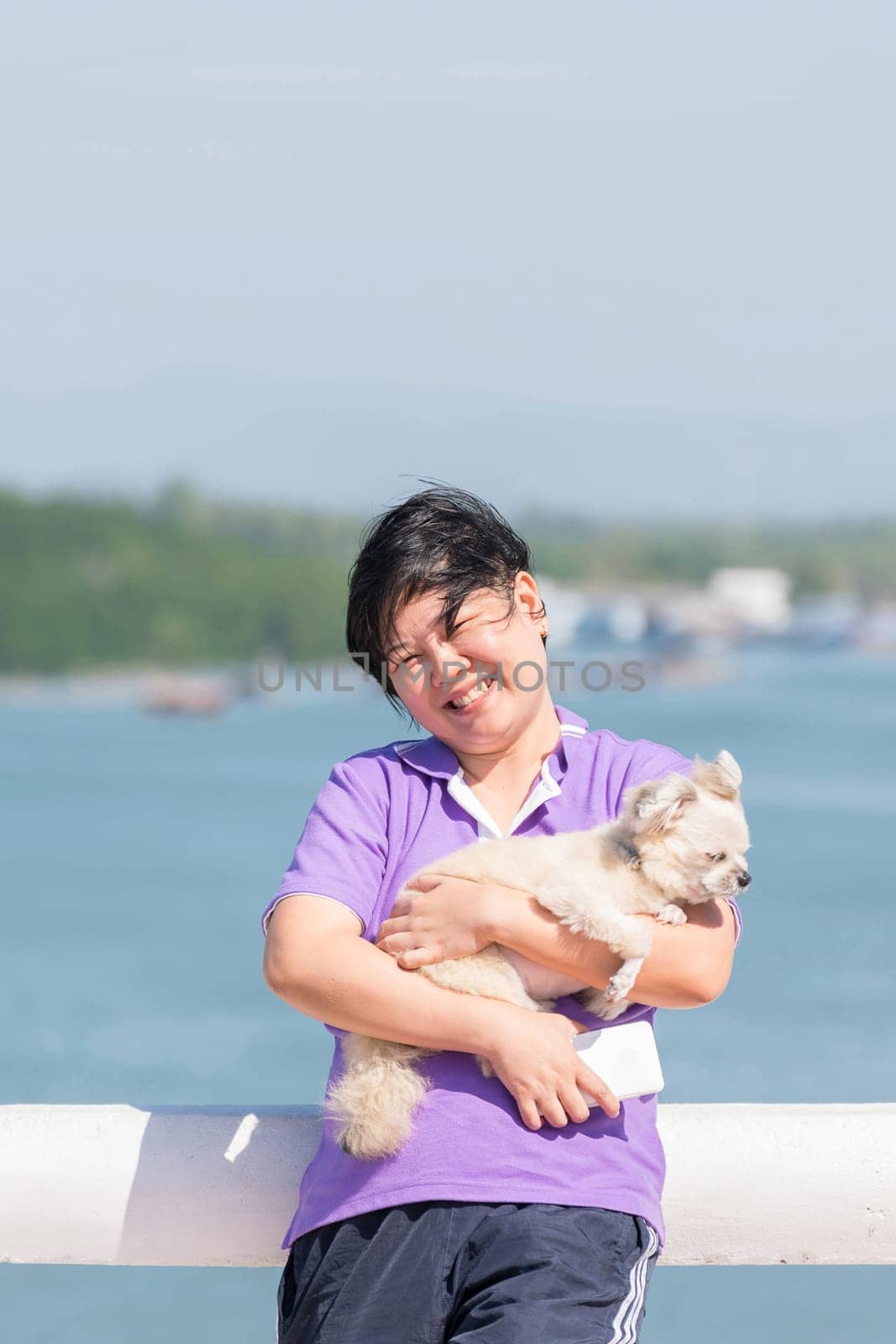 Asia woman plump body and her dog standing at estuary (river side and sea) when travel