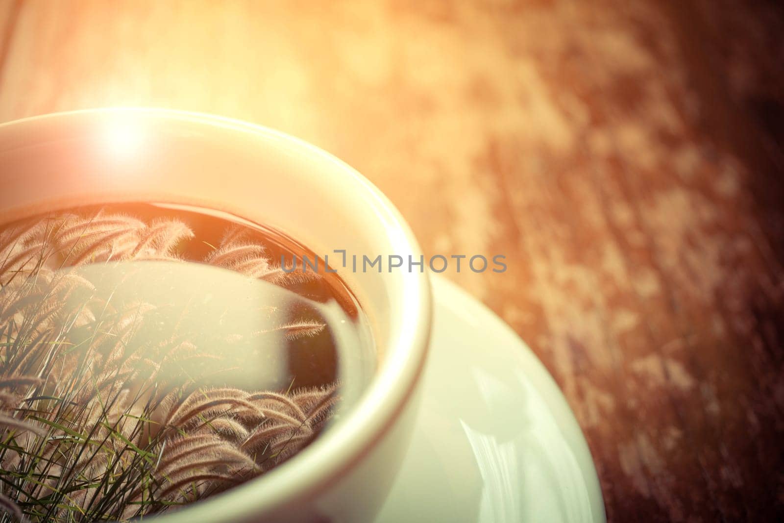 Grass flower (poaceae) reflection on Coffee in white cup on wood table , process in vintage style
