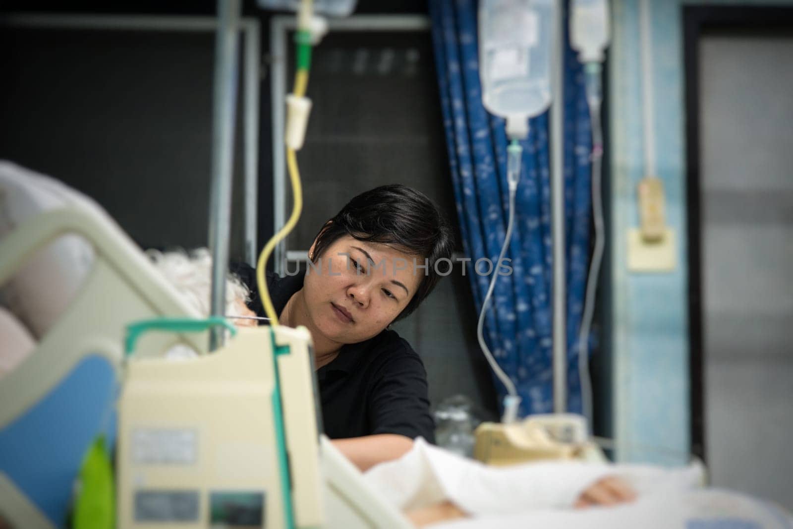 Asian women 40s years old is a patient relative taking care of the CRE. or VRE. infected elder patient 80s years old on bed in the hospital.