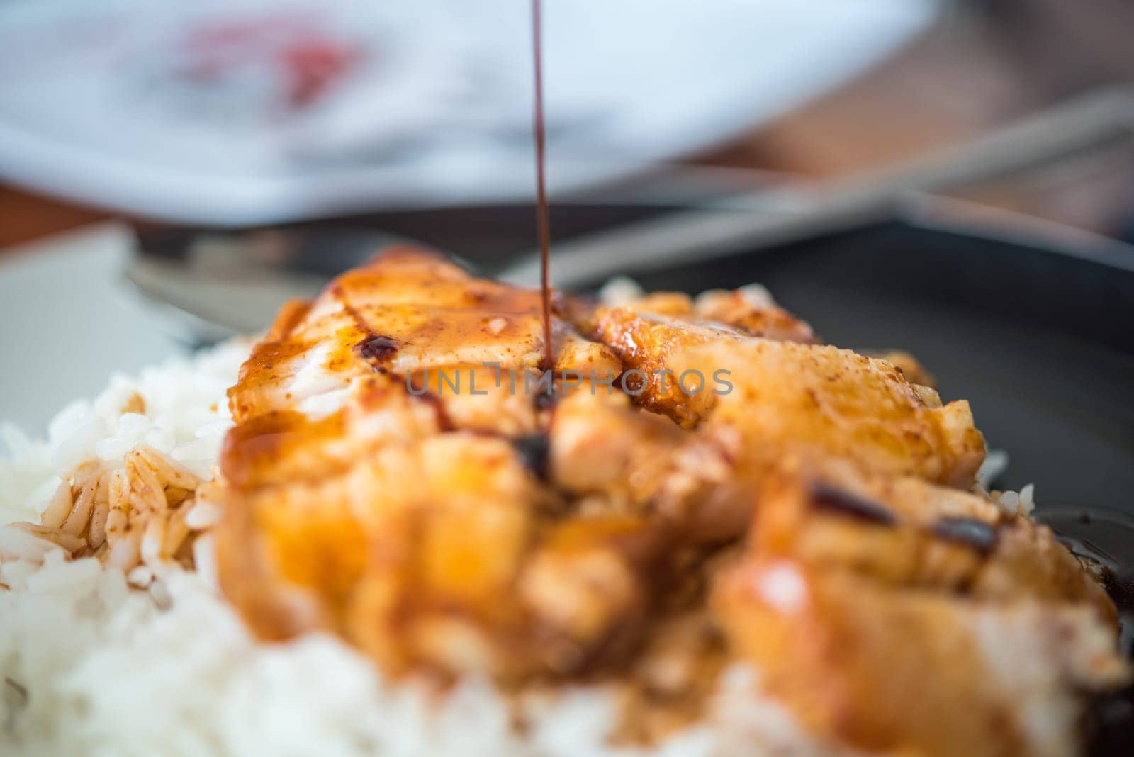 Barbecued red pork in sauce with rice and cucumber served in dish on wood table in Thai restaurant at Thai street food market at Bangkok Thailand