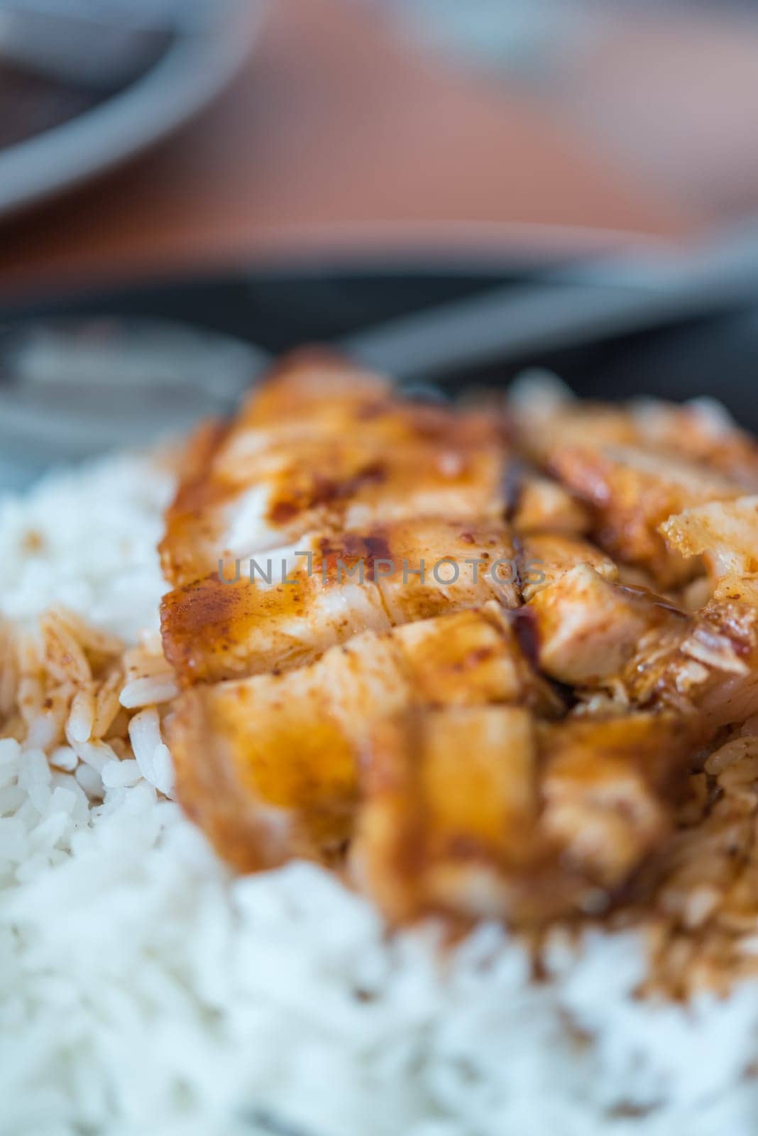 Barbecued red pork in sauce with rice and cucumber served in dish on wood table in Thai restaurant at Thai street food market at Bangkok Thailand