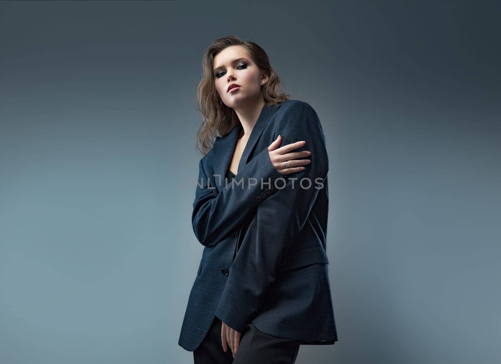 A stylish studio photoshoot featuring a model wearing a chic blazer over a trendy top, set against a neutral background. Perfect for highlighting modern fashion and elegant styling