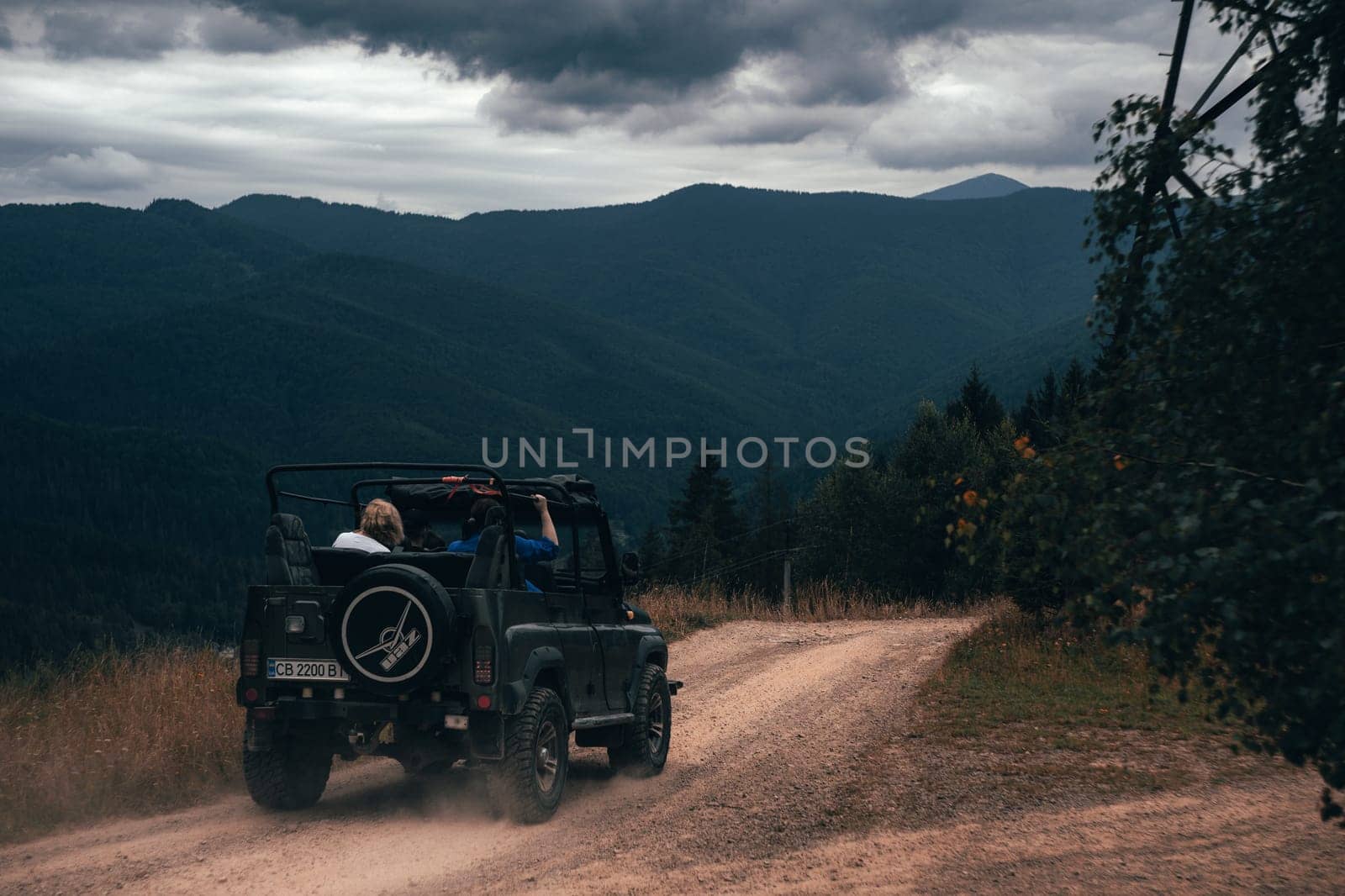 This photo captures an adventurous journey through the mountains, with a rough road twisting through the wilderness. Dark clouds loom overhead, setting the mood for an exciting off-road experience.