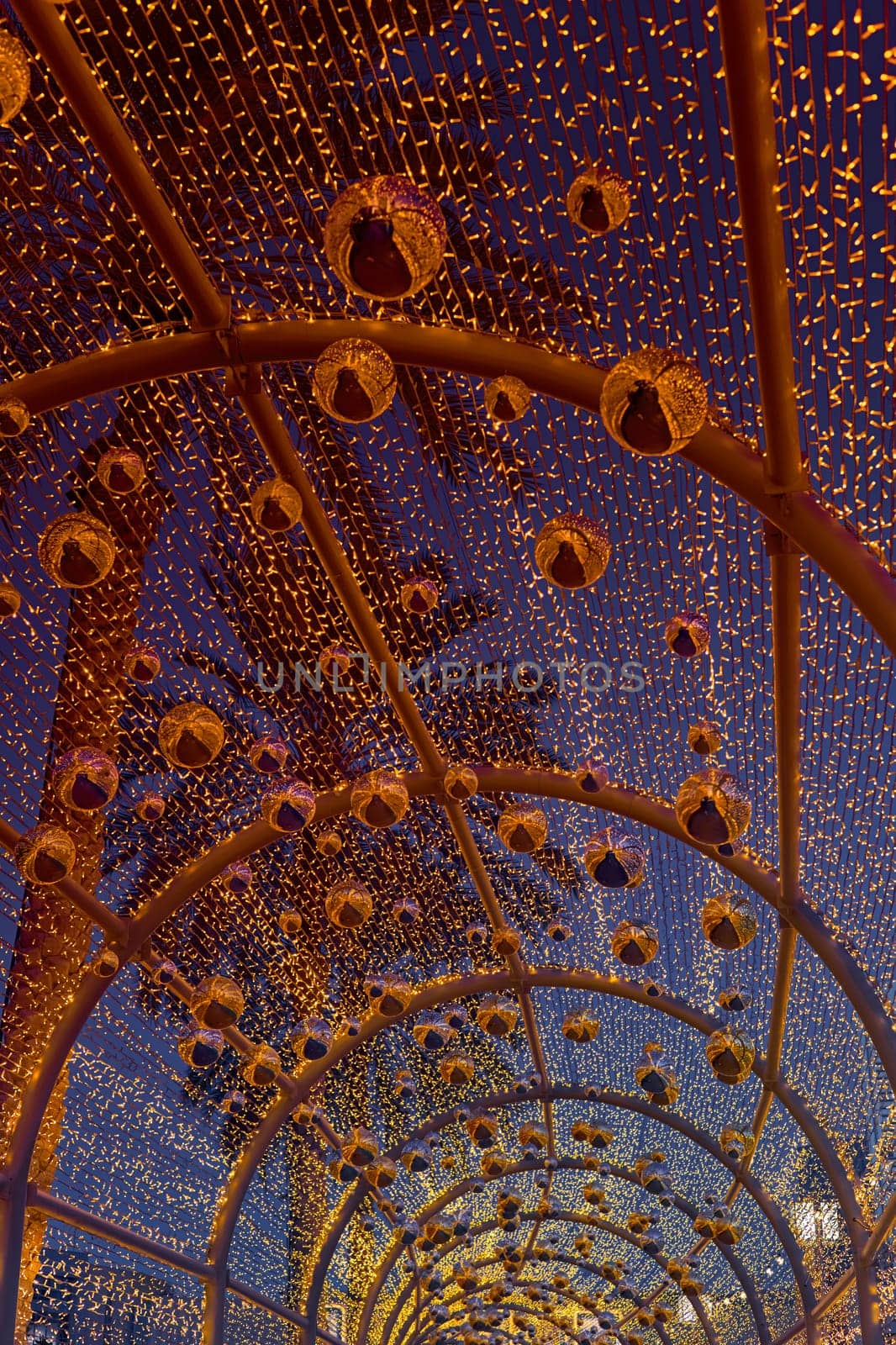 an alley decorated with New Year's garlands and golden balls in center of Dubai at dusk, Christmas decorations with palm trees on the background. High quality photo