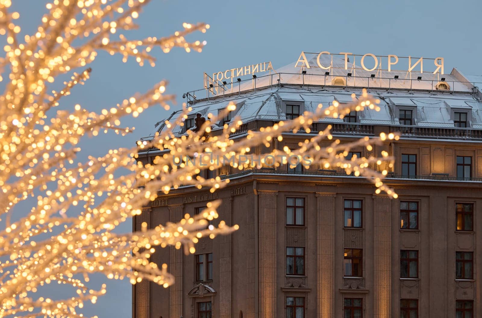 Russia, St.Petersburg, 30 December 2023: the famous Astoria hotel, a snow-covered New Year's city decorated for the celebration of the new year, walking tourists. High quality photo