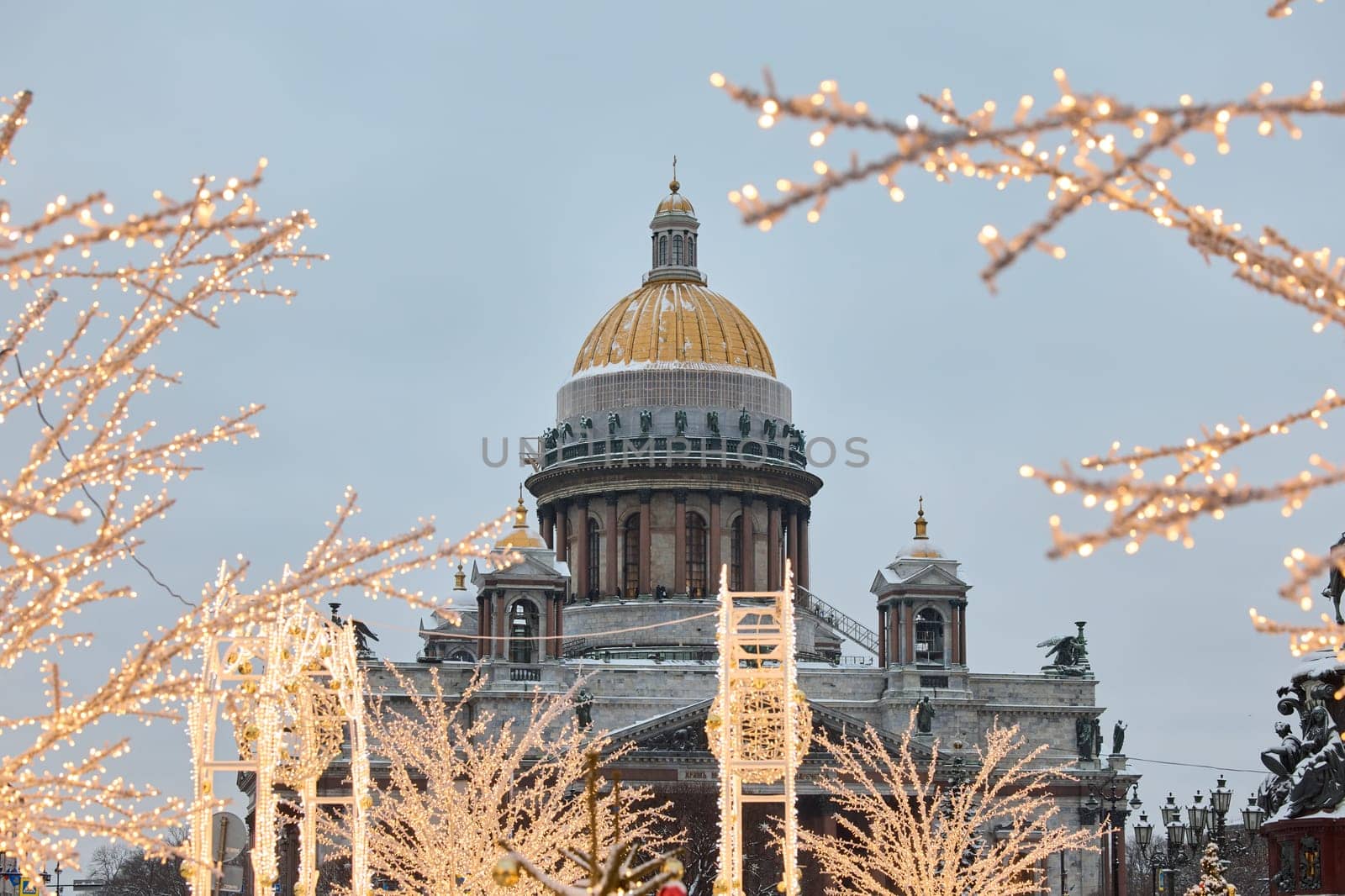 a snow-covered New Year's city decorated for the celebration of the new year, the golden dome of St. Isaac's Cathedral, walking tourists. High quality photo