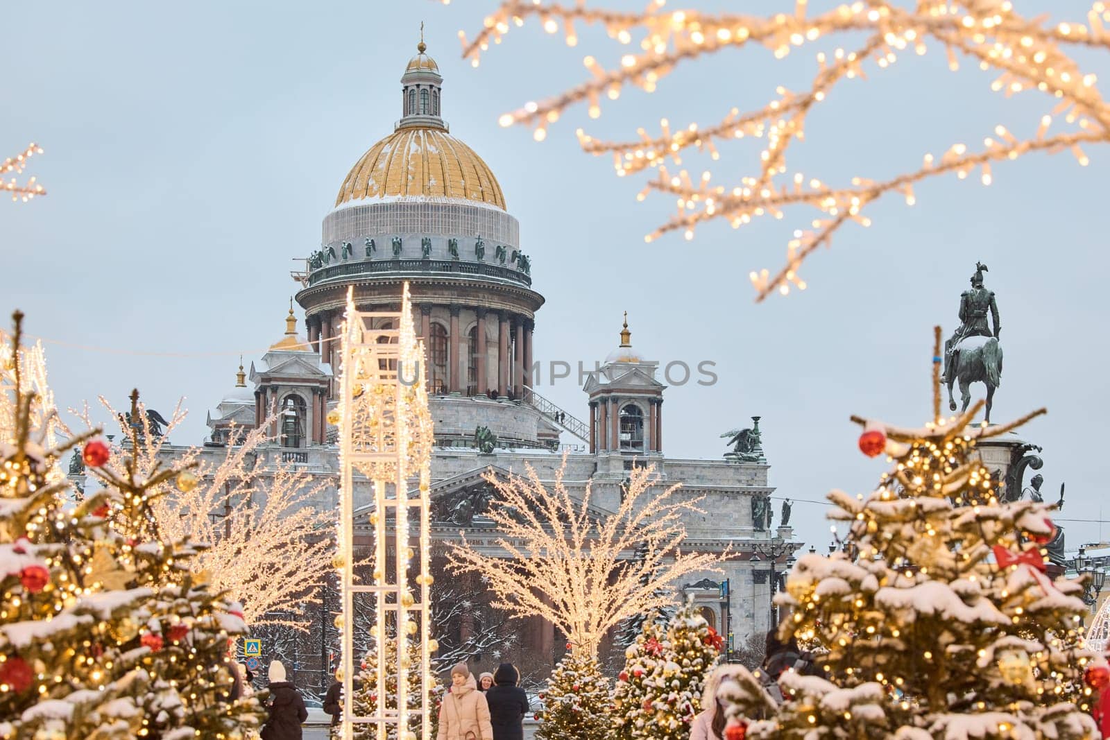 Russia, St.Petersburg, 30 December 2023: a snow-covered New Year's city decorated for the celebration of the new year, the golden dome of St. Isaac's Cathedral, walking tourists. High quality photo