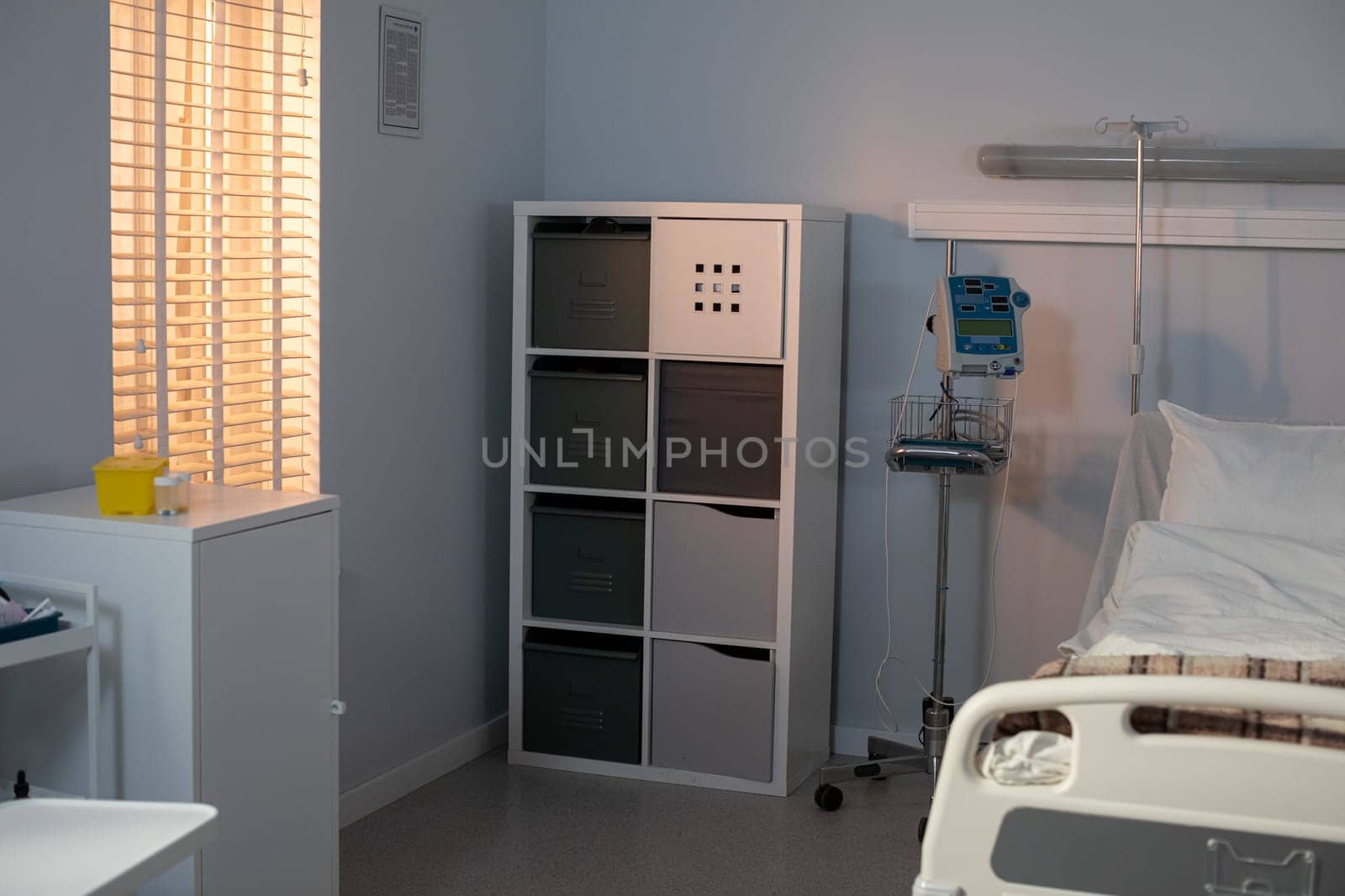 This hospital room is bright and inviting, featuring a comfy bed, essential medical equipment, and organized storage