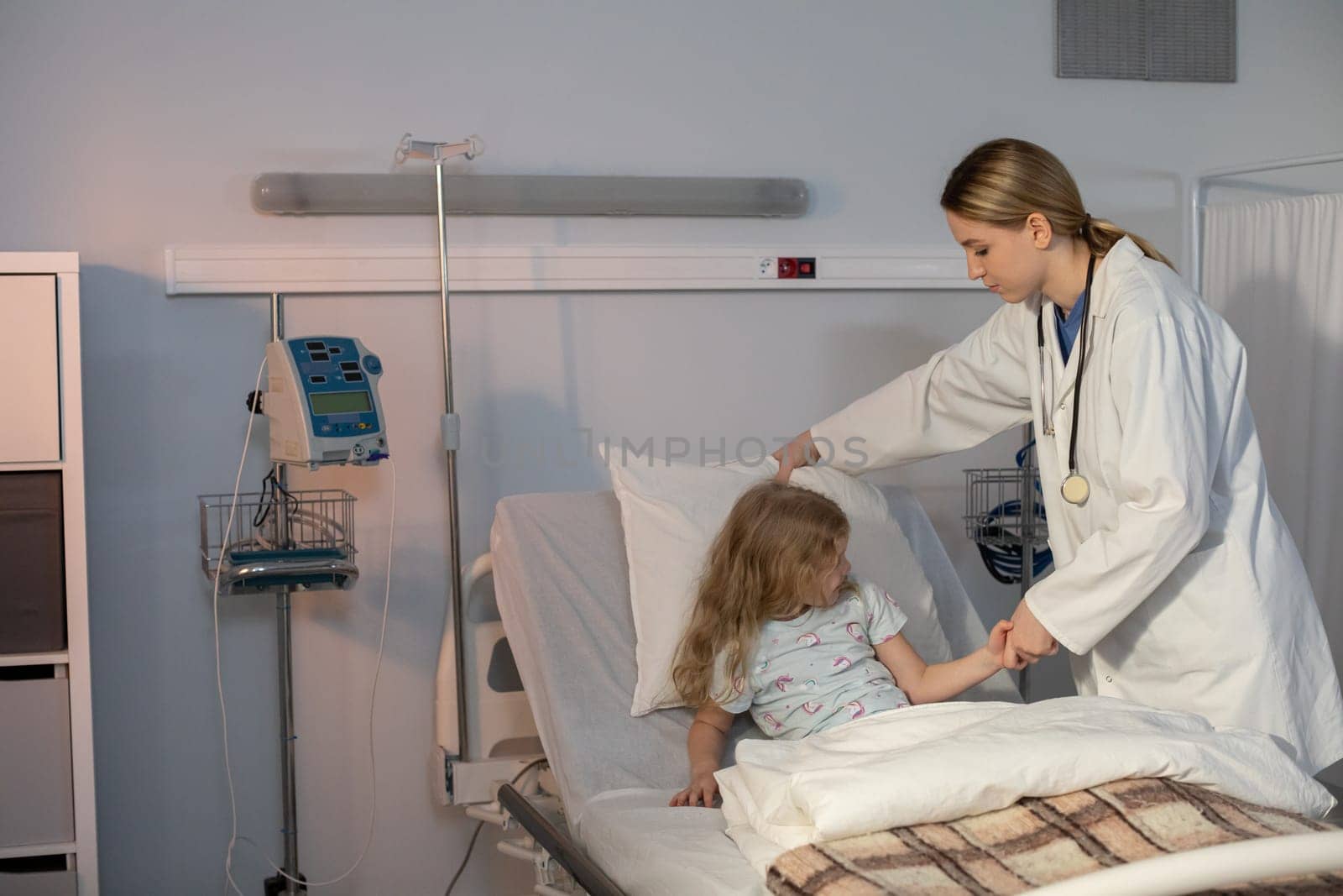 A compassionate nurse aids a young girl in a hospital setting, showcasing healthcare professionalism.
