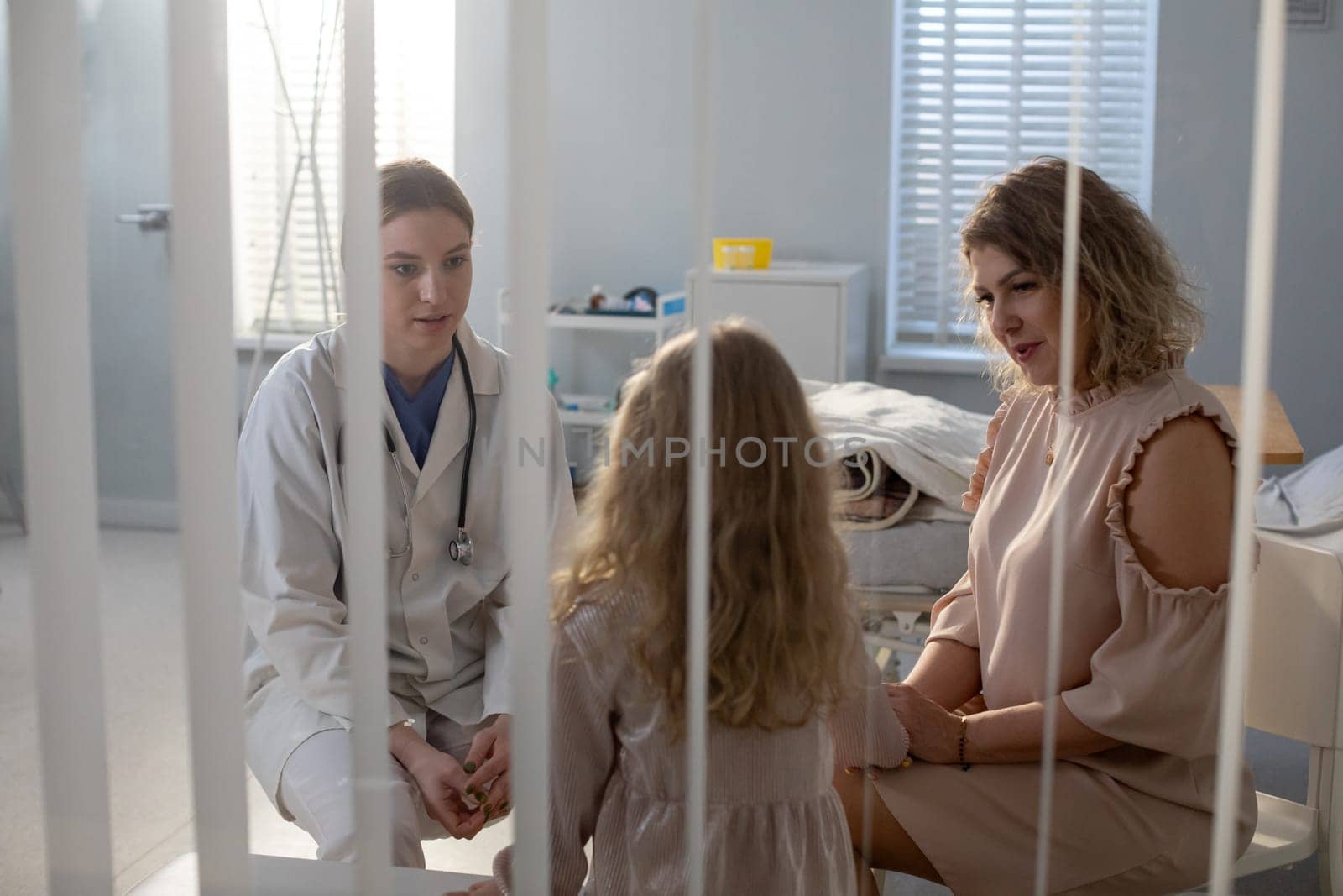 In a warm hospital, a doctor speaks compassionately with a child and her mother, highlighting empathys importance