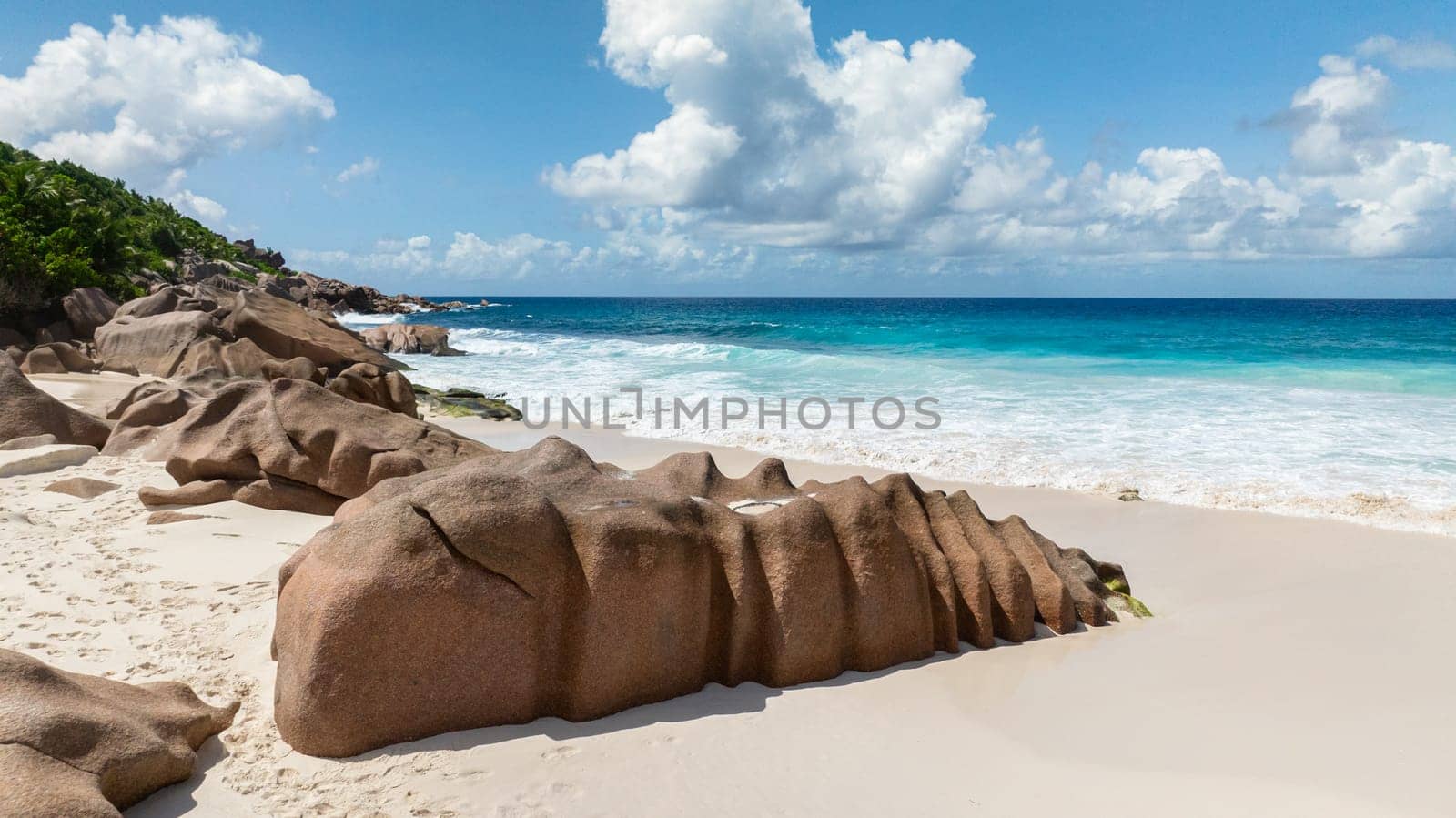 Granite rocks and tropical plants by the white sandy beach. Anse Cocos beach. La Digue, Seychelles.