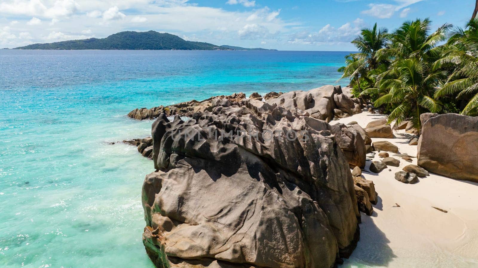 Natural rock formations and crystal clear water on a tranquil sandy beach. La Digue, Seychelles.