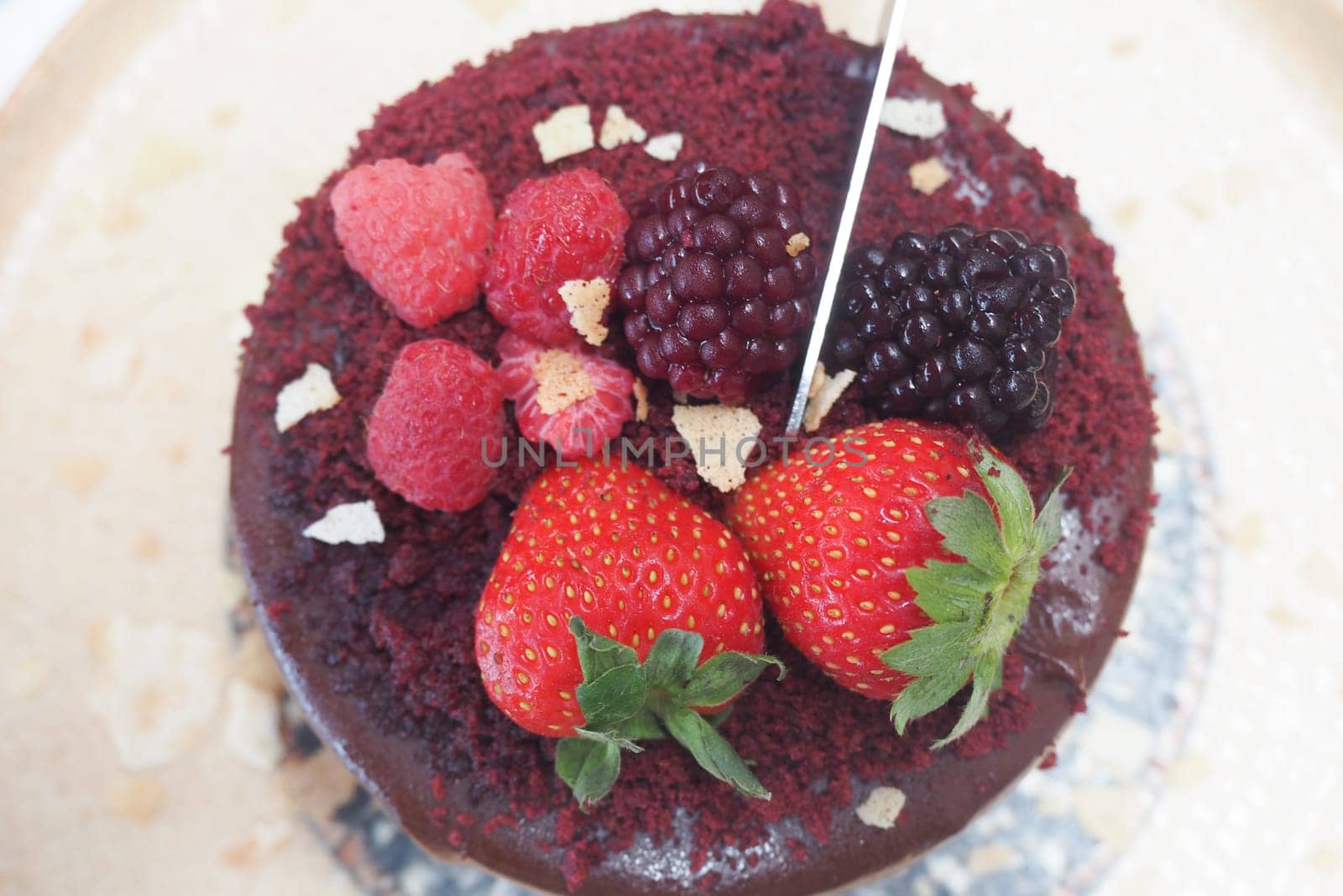 A beautifully decorated red velvet cake with strawberries and raspberries.