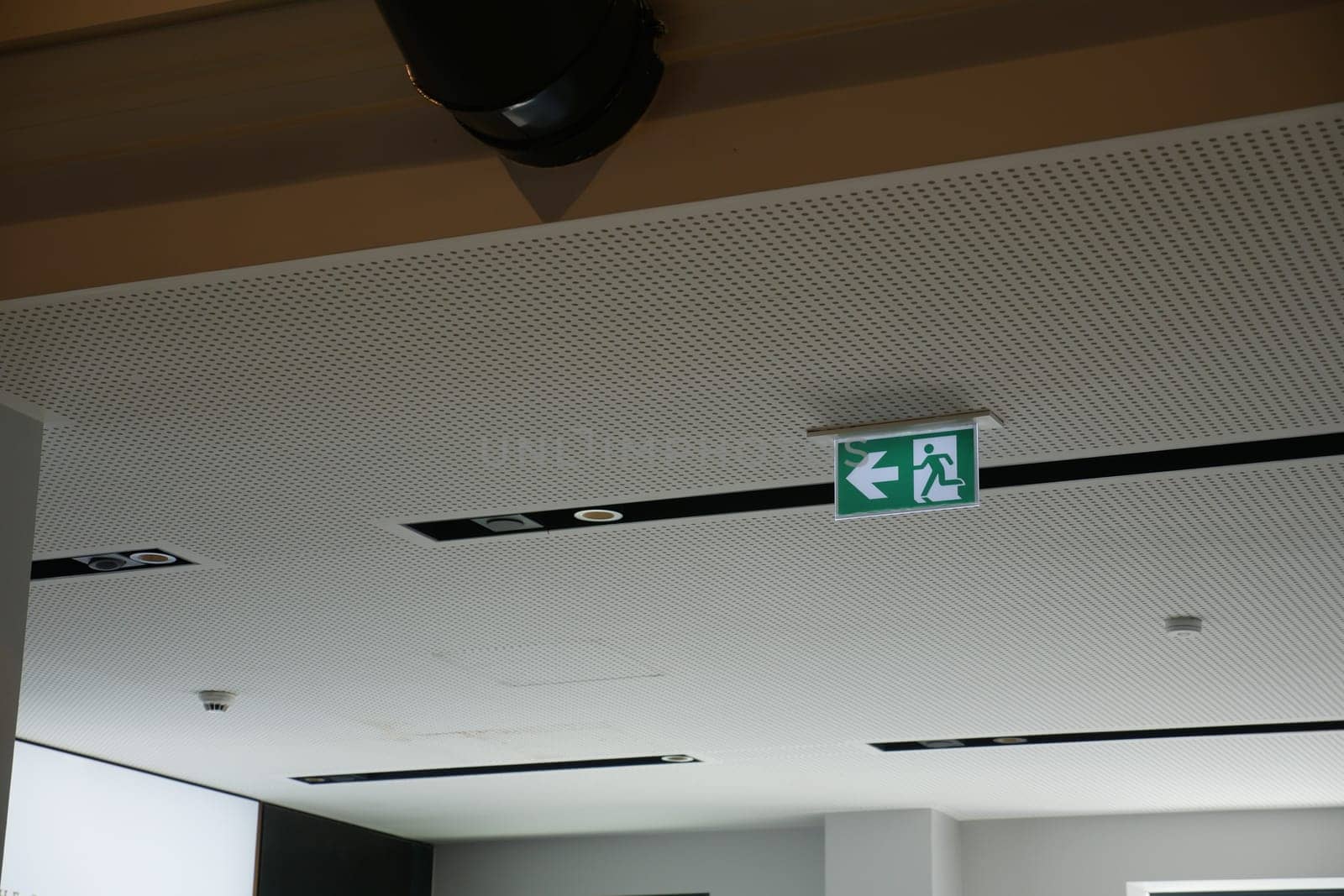 Clear escape route indicated by green emergency sign above walkway.