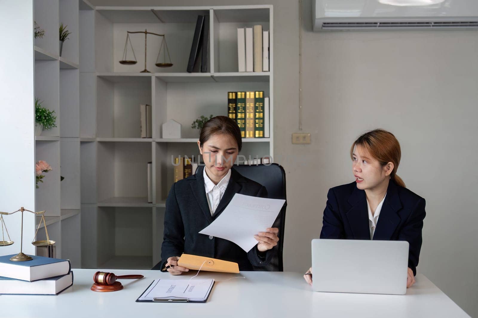 A lawyer examining important legal documents and discussing them with a client in a modern office environment.