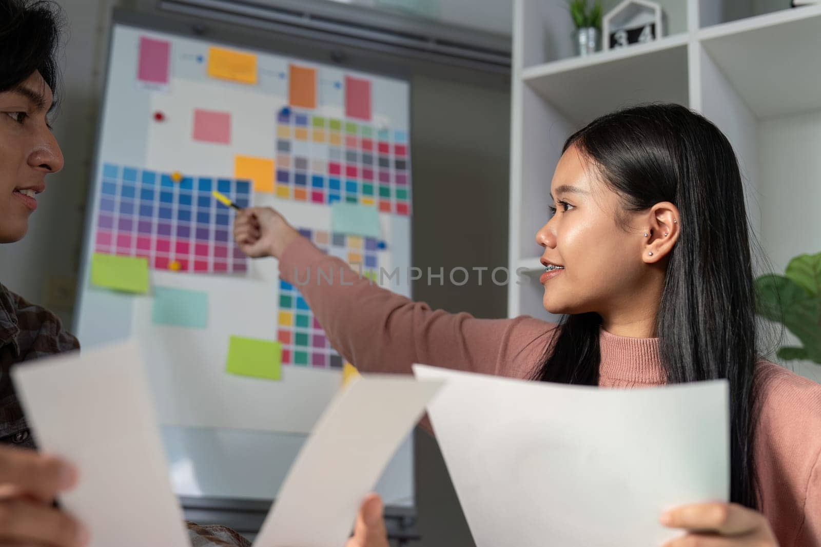 A diverse graphic design team collaborating and showcasing color palettes while discussing project ideas in a creative workspace.