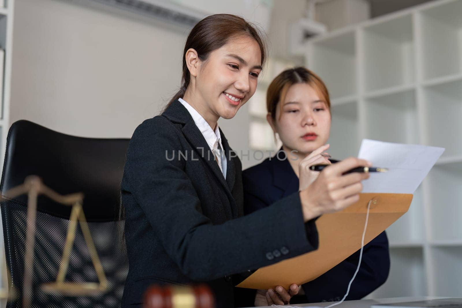 A lawyer joyfully explaining legal documents to a client, showcasing collaboration in a professional office environment with a gavel present.