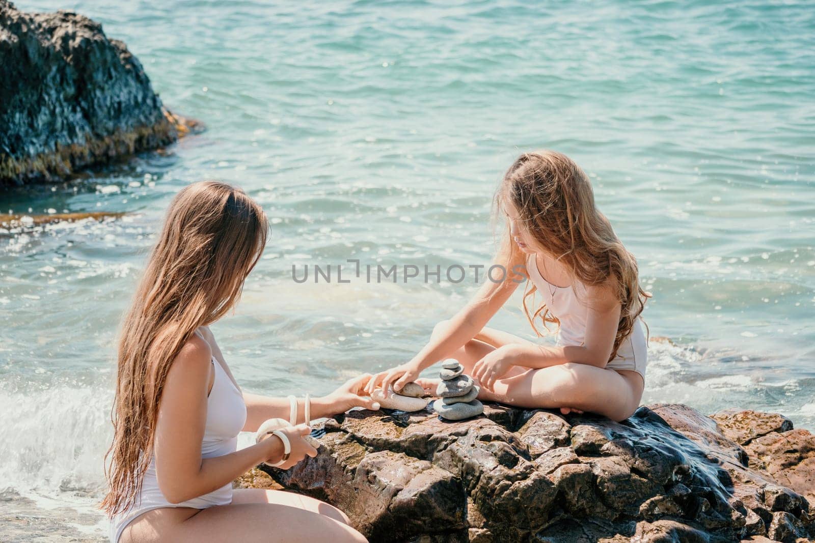 Balanced Pebbles Pyramid on the Beach on Sunny Day and Clear Sky at Sunset. Blue Sea on Background Selective focus, zen stones on sea beach, meditation, spa, harmony, calm, balance concept.