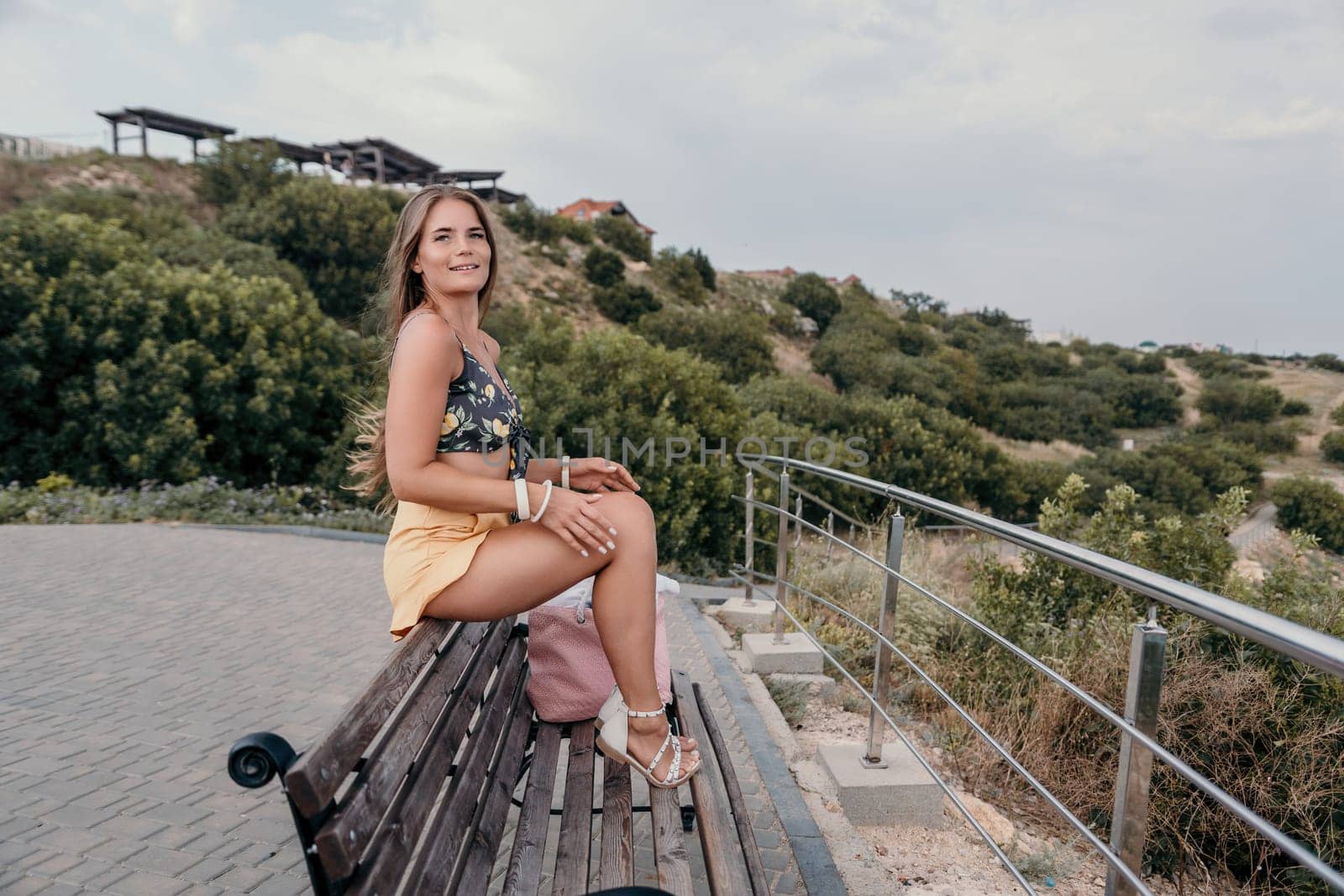 Woman travel sea. Happy tourist taking picture outdoors for memories. Woman traveler looks at the edge of the cliff on the sea bay of mountains, sharing travel adventure journey.