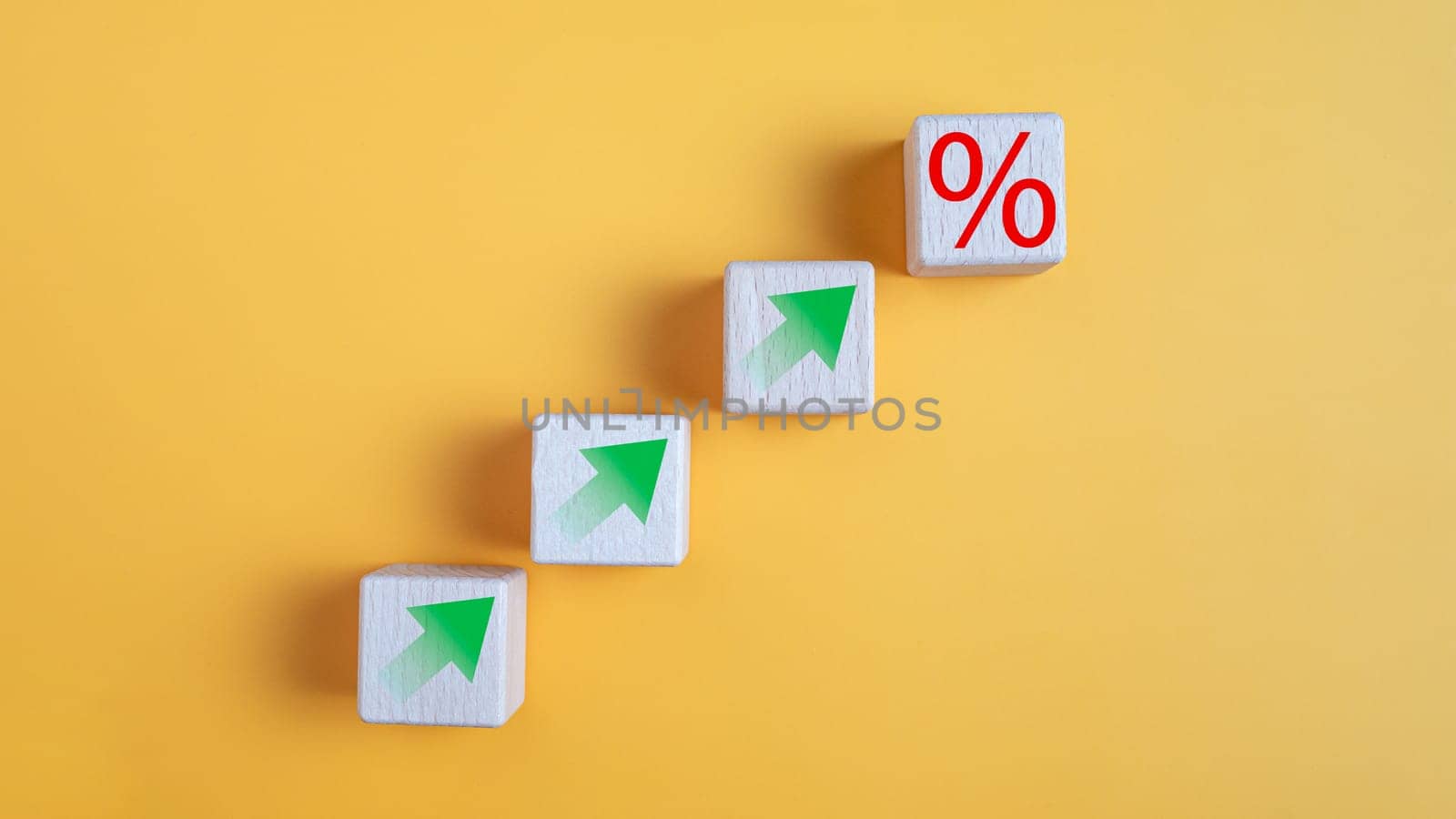 Wooden block with percentage symbol and up arrow on yellow background. Interest rate and dividend concept,  return on stocks and mutual funds, long term investment for retirement.