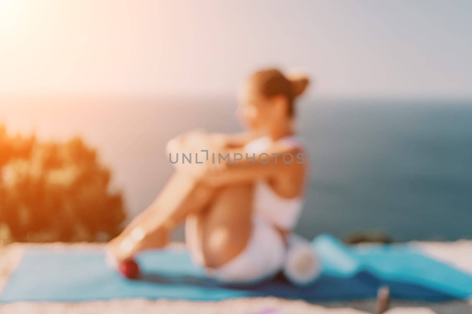 Abstract defocused fitness woman sea. A happy middle aged woman in white sportswear exercises morning outdoors in a park with a beach view. Female fitness pilates yoga routine concept. Healthy lifestyle. by panophotograph