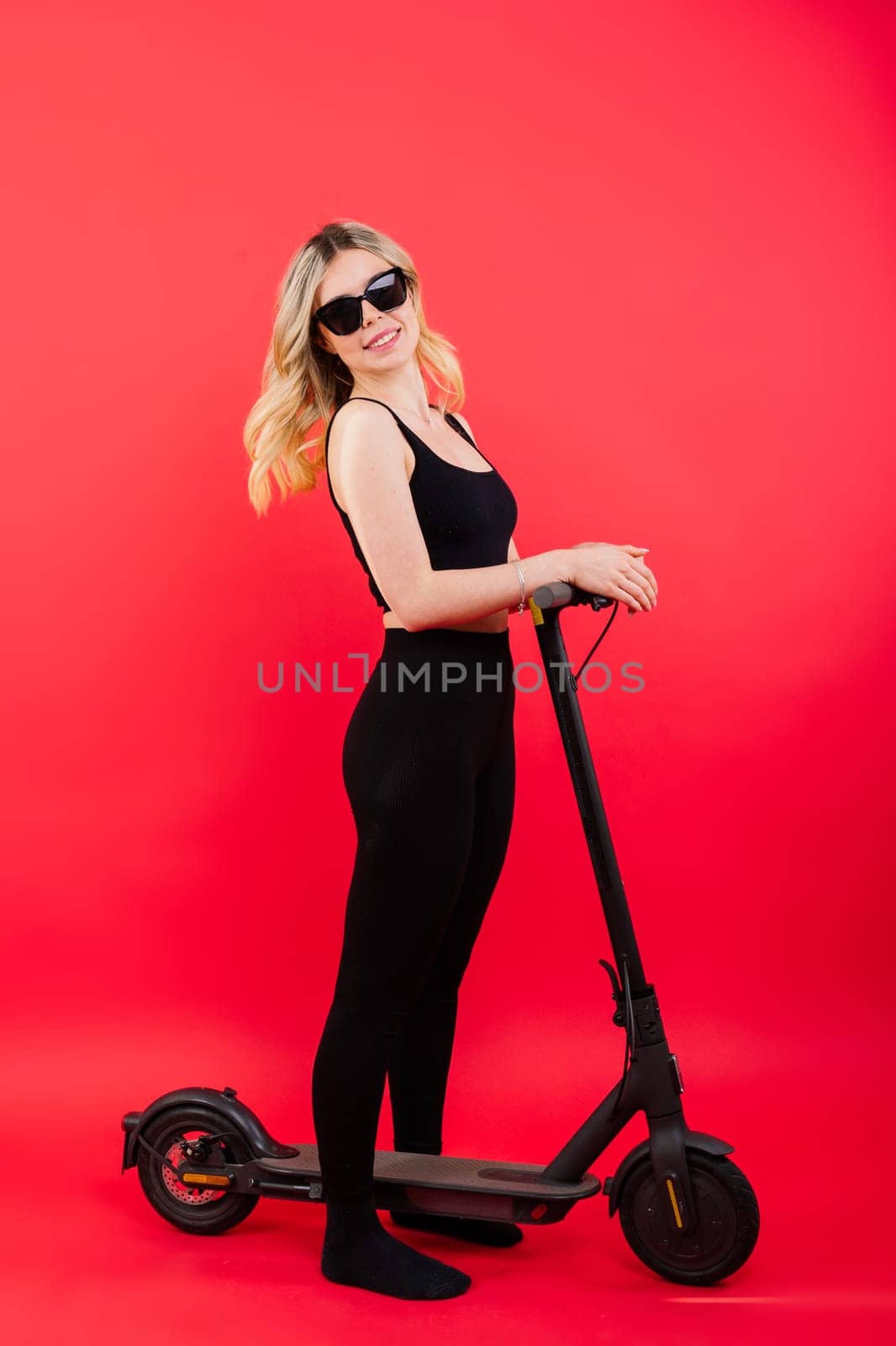 Blonde woman on red and white background sit and stand with electro scooter and resting by Zelenin