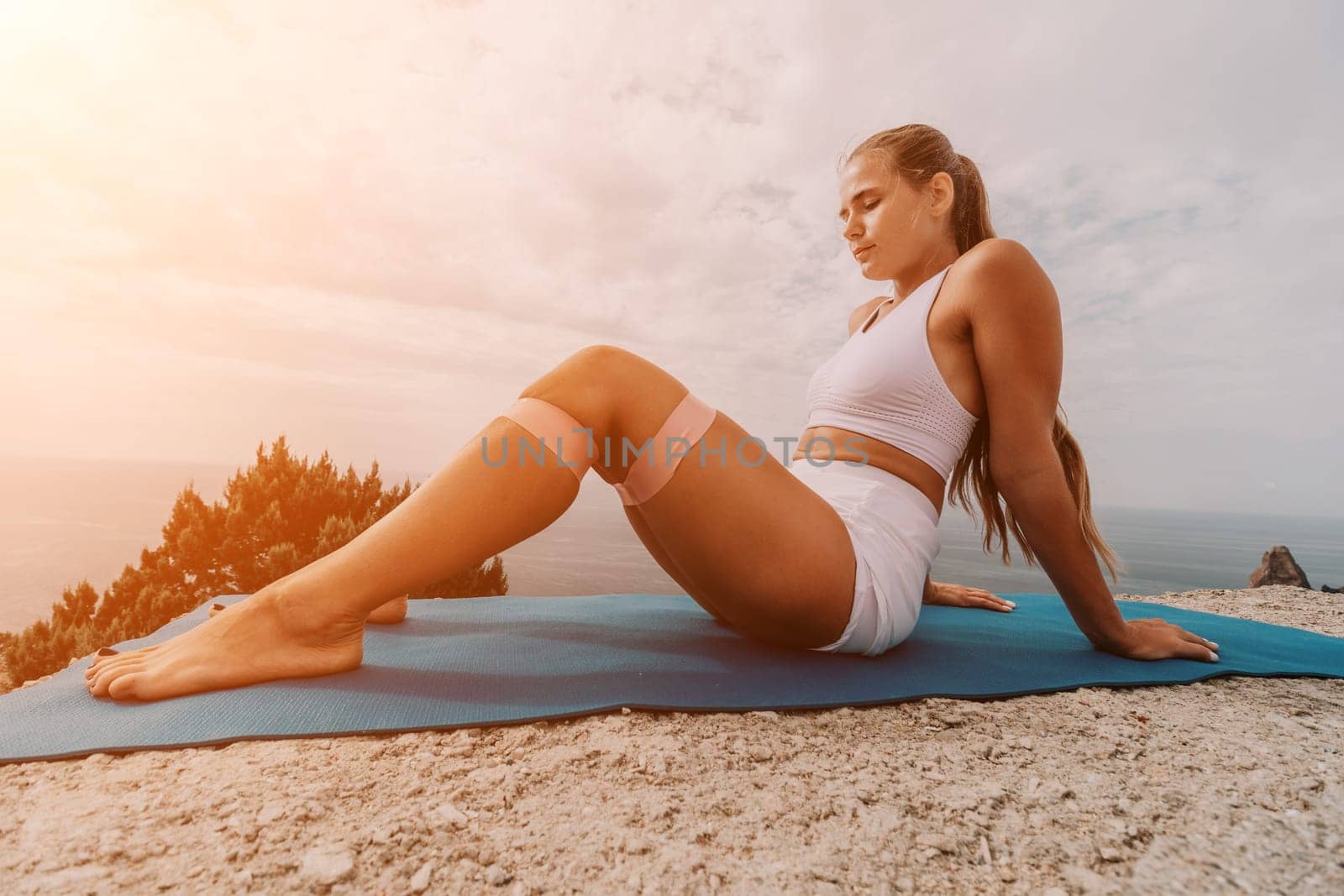 Woman sea pilates. Sporty, middle-aged woman practicing pilates in park near the sea. trains on a yoga mat and exudes a happy and active demeanor. healthy lifestyle through exercise and meditation. by panophotograph