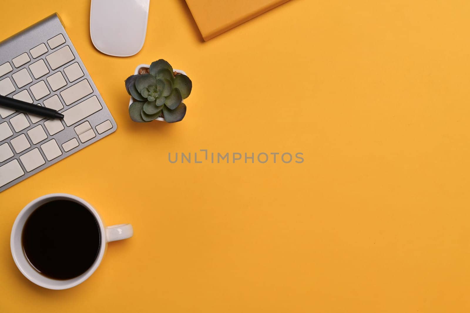 Top view of coffee cup, keyboard and notebook on yellow background. Space for text advertising text message.