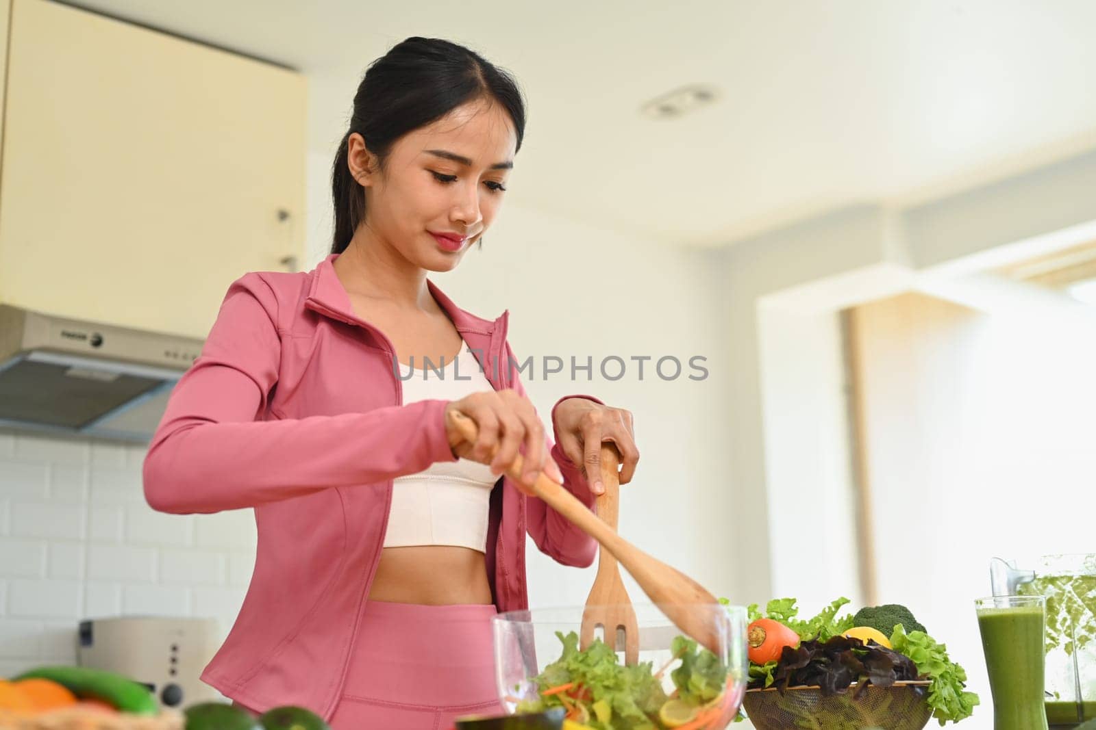 Young sporty woman making vegetable salad in kitchen. Dieting, health lifestyle and nutrition concept.