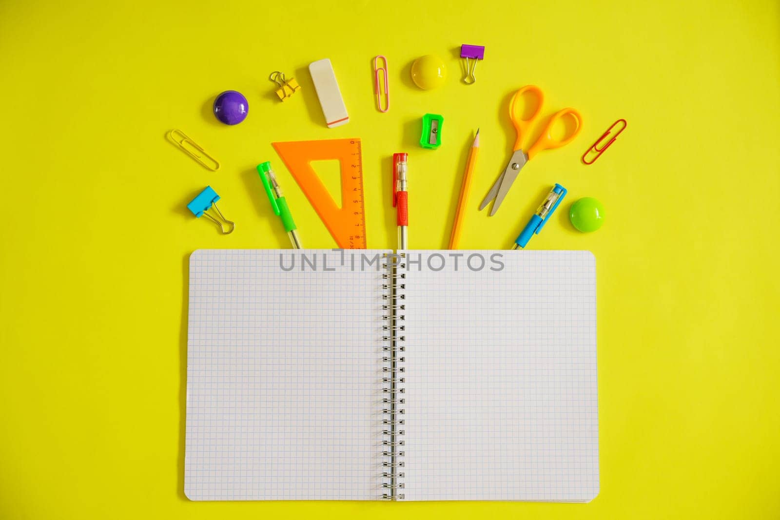 Notebook on a spring for notes and stationery lie on a yellow background, the concept of back to school, colorful school supplies