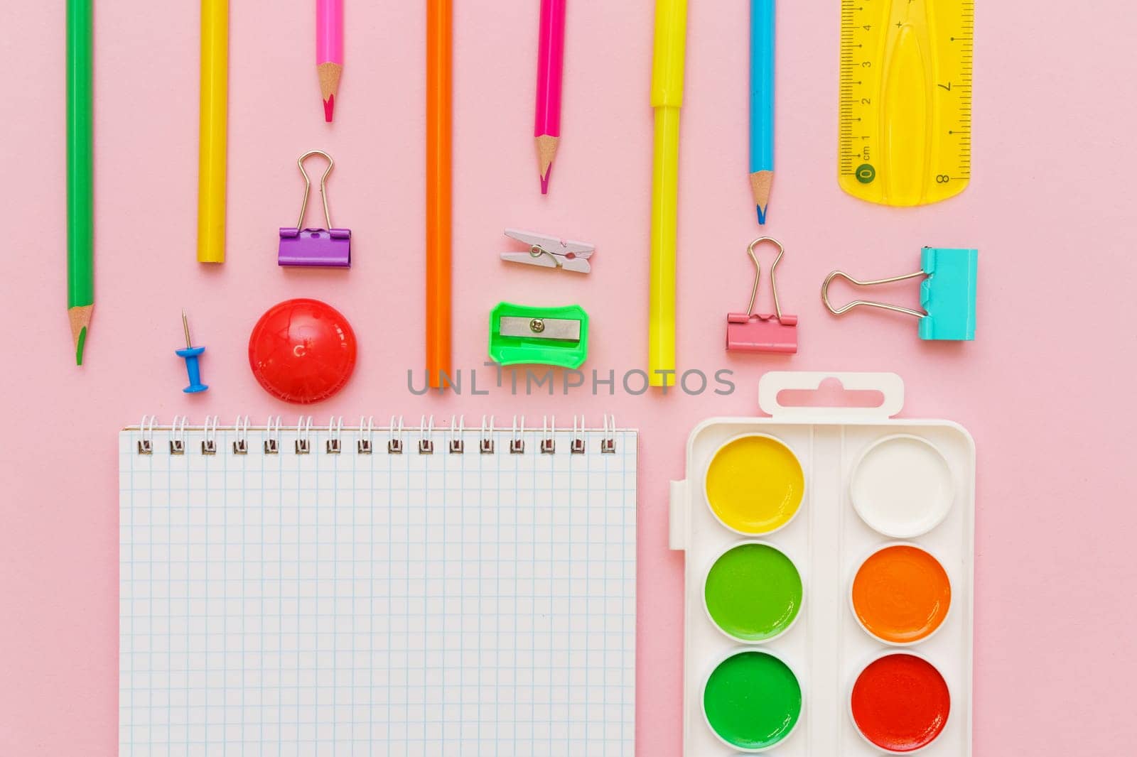 Supplies creative tools for school creative work on pink background with pattern stationery, colored paints brushes pencils, pens notepad on a spiral copy space, flat set, mock up