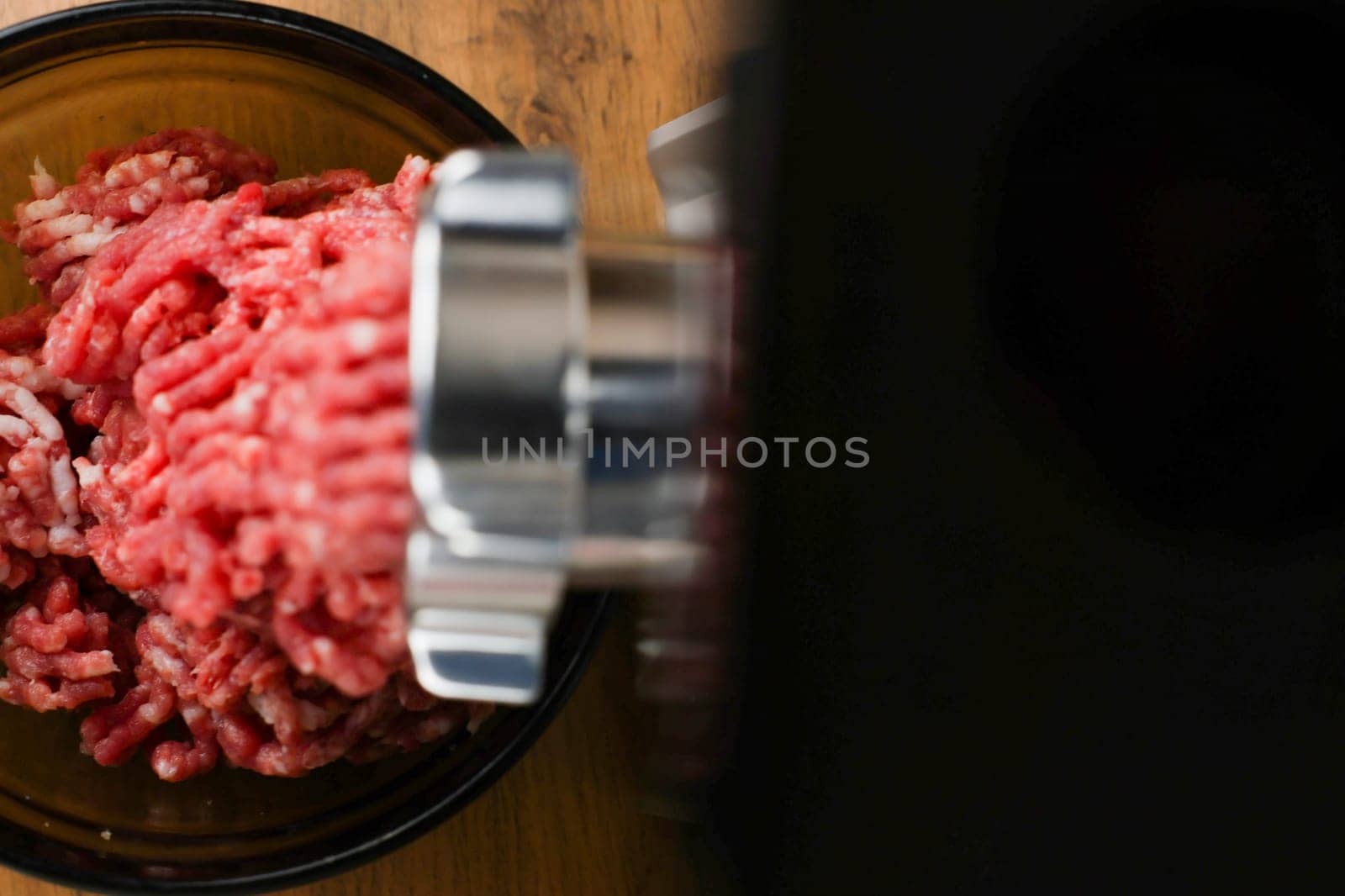 The concept of healthy and proper nutrition, cooking. Top and left view of red ground beef with streaks of fat coming out of a metal grinder with space for text on the right on a black background. High quality photo