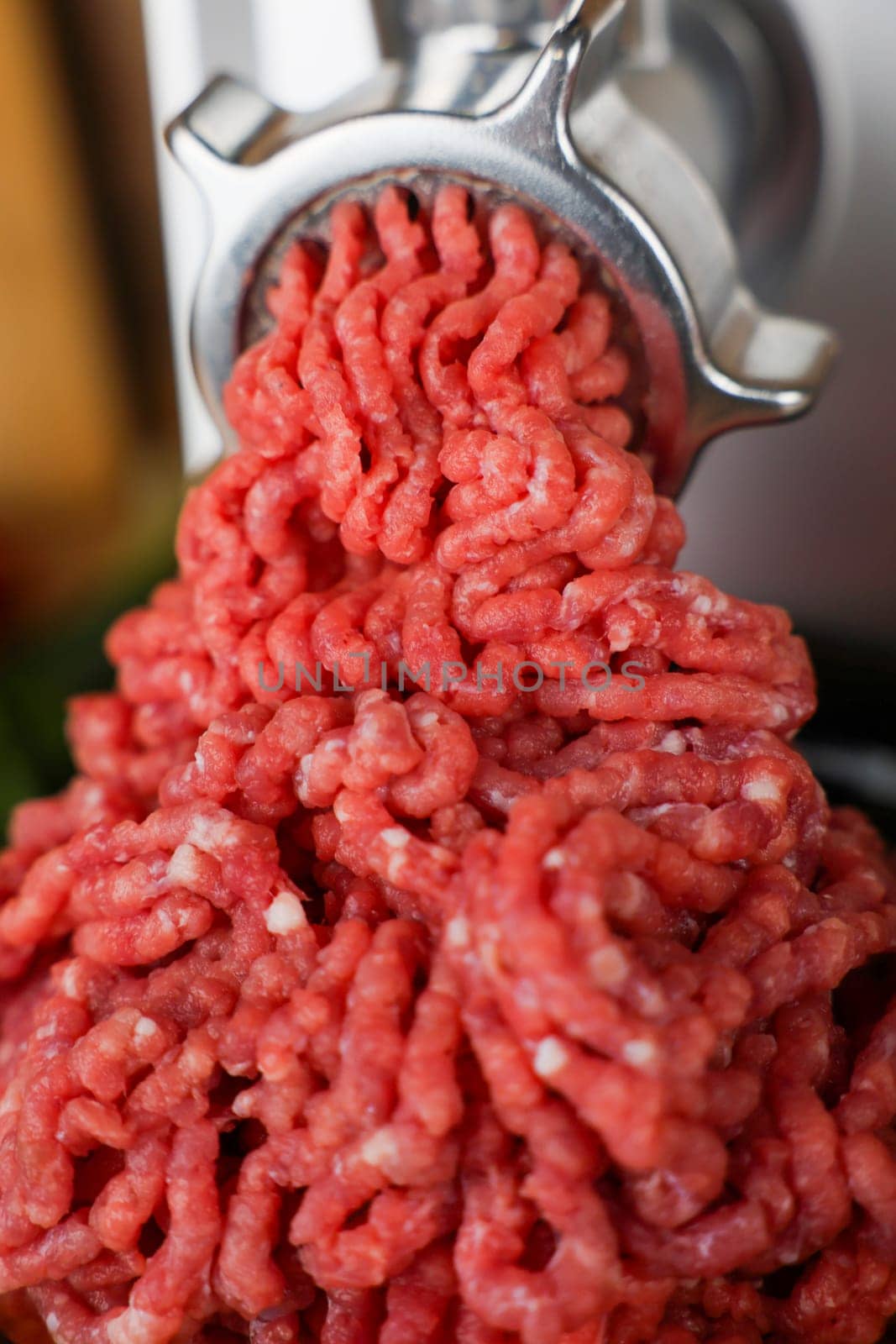 The concept of healthy and proper nutrition, cooking. A close-up view from above of red ground beef with streaks of fat, which comes out of the metal grinder in waves and takes up most of the photo. High quality photo