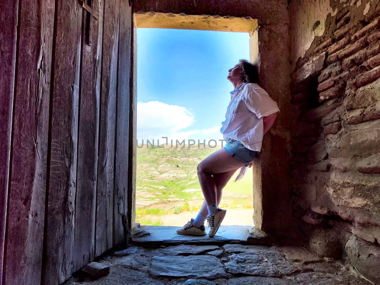 A mature woman enjoys a peaceful moment exploring beautiful landscapes, reflecting on her travels.