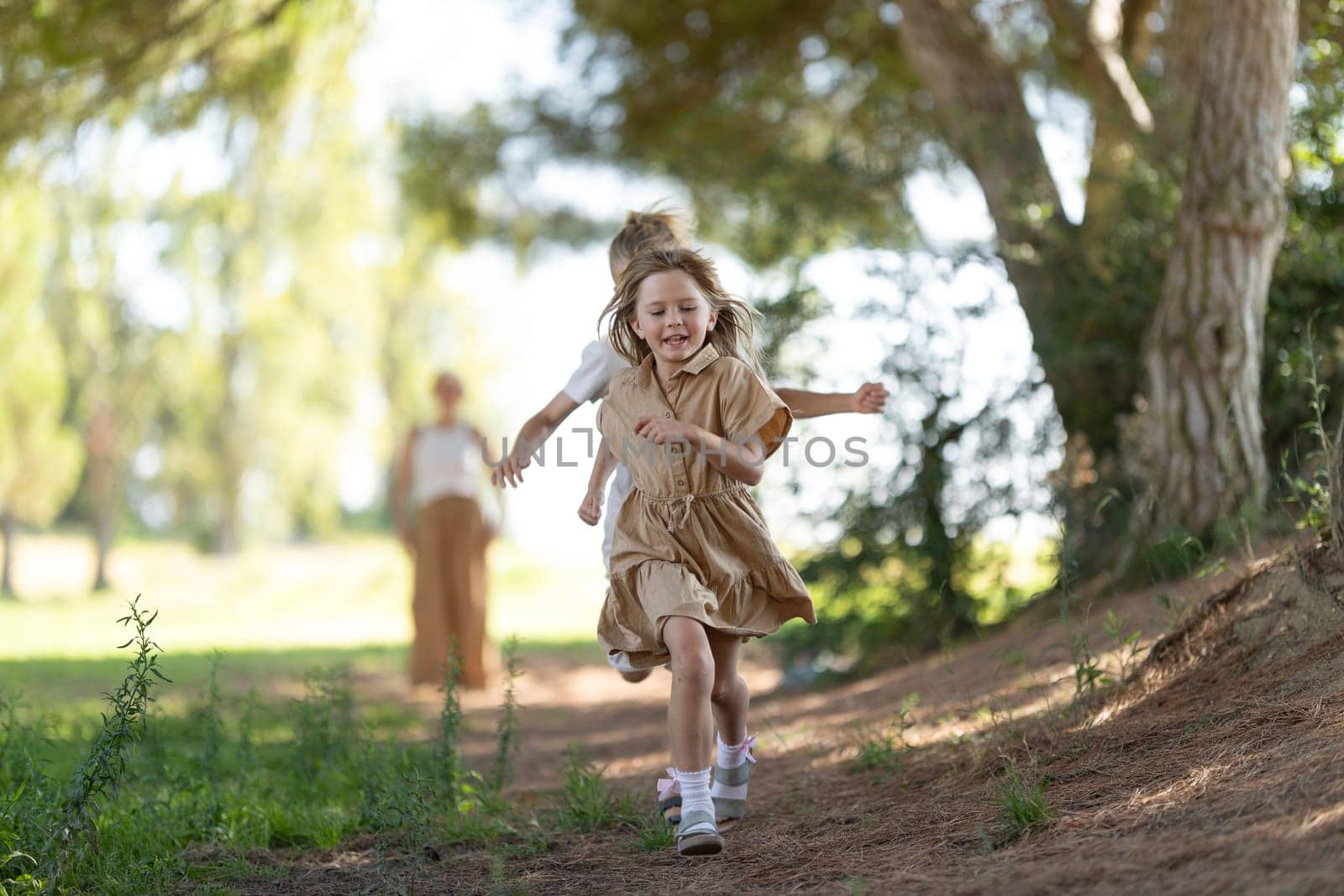 Happy children playing and running in a sunlit forest path