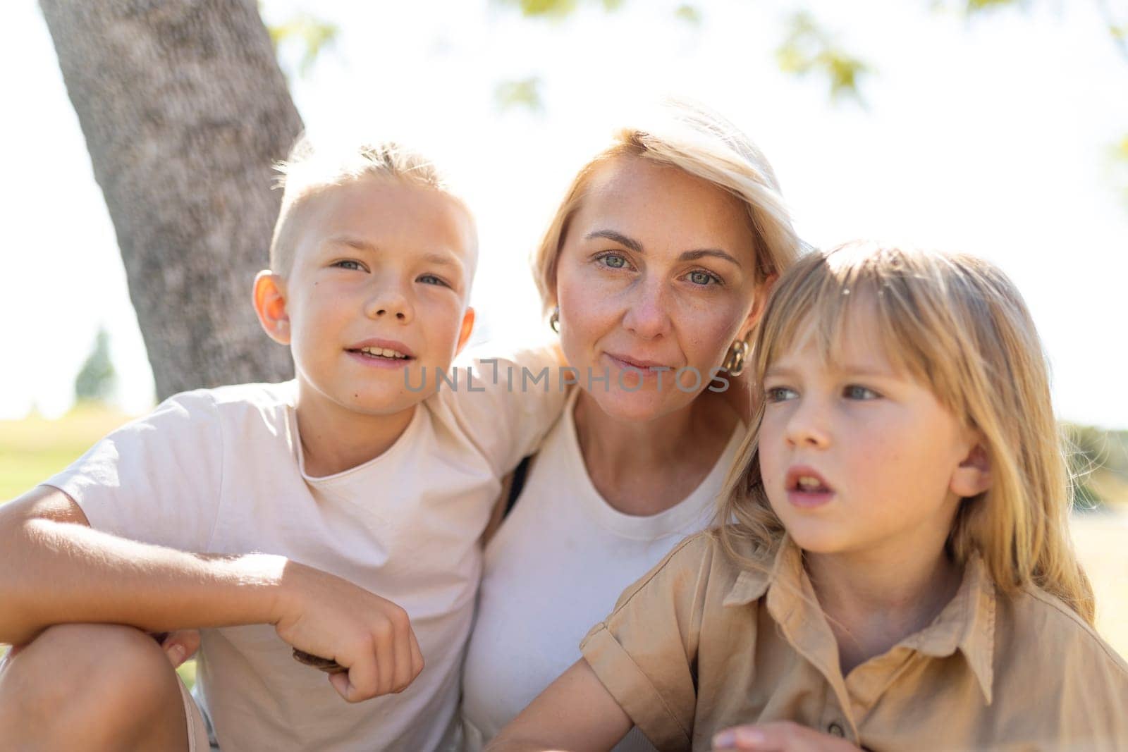 Mother and two children sitting together under a tree