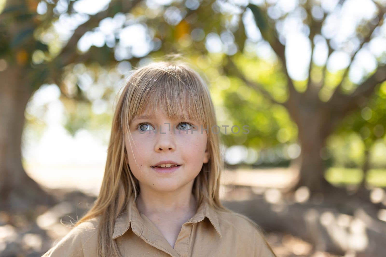 Smiling girl standing outdoors under large trees