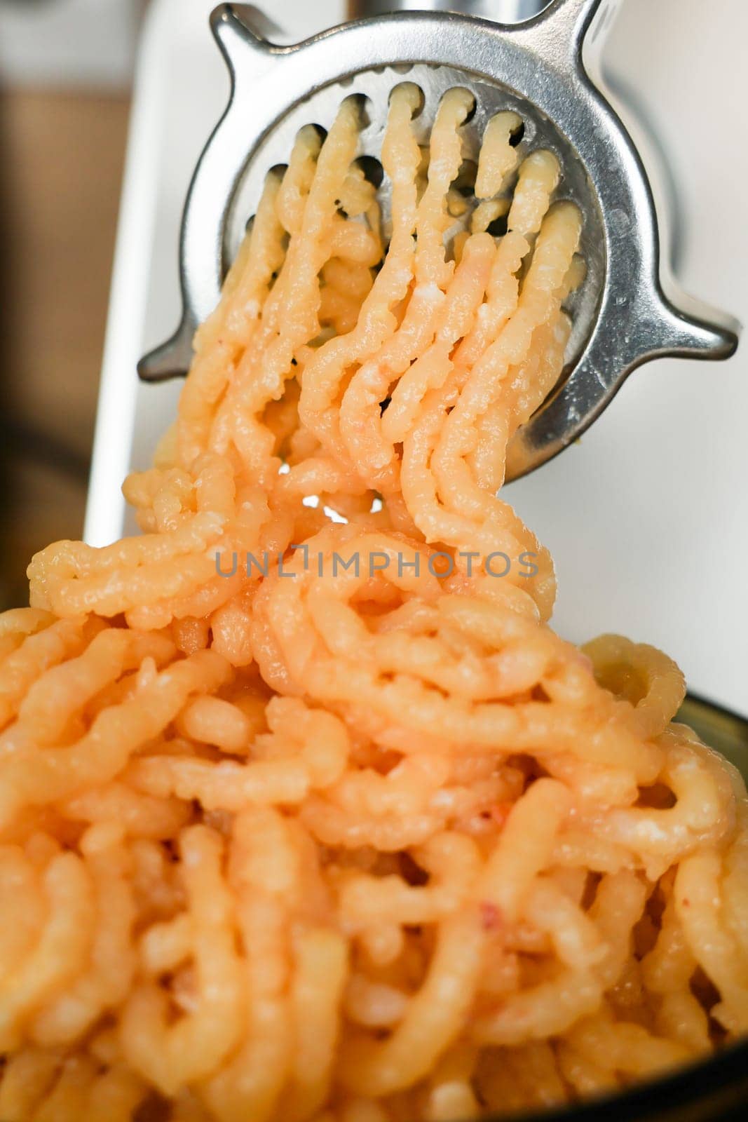 Close-up of minced chicken comes out of a metal meat grinder. The concept of dietary recipes, proper and healthy nutrition, the cooking process. High quality photo