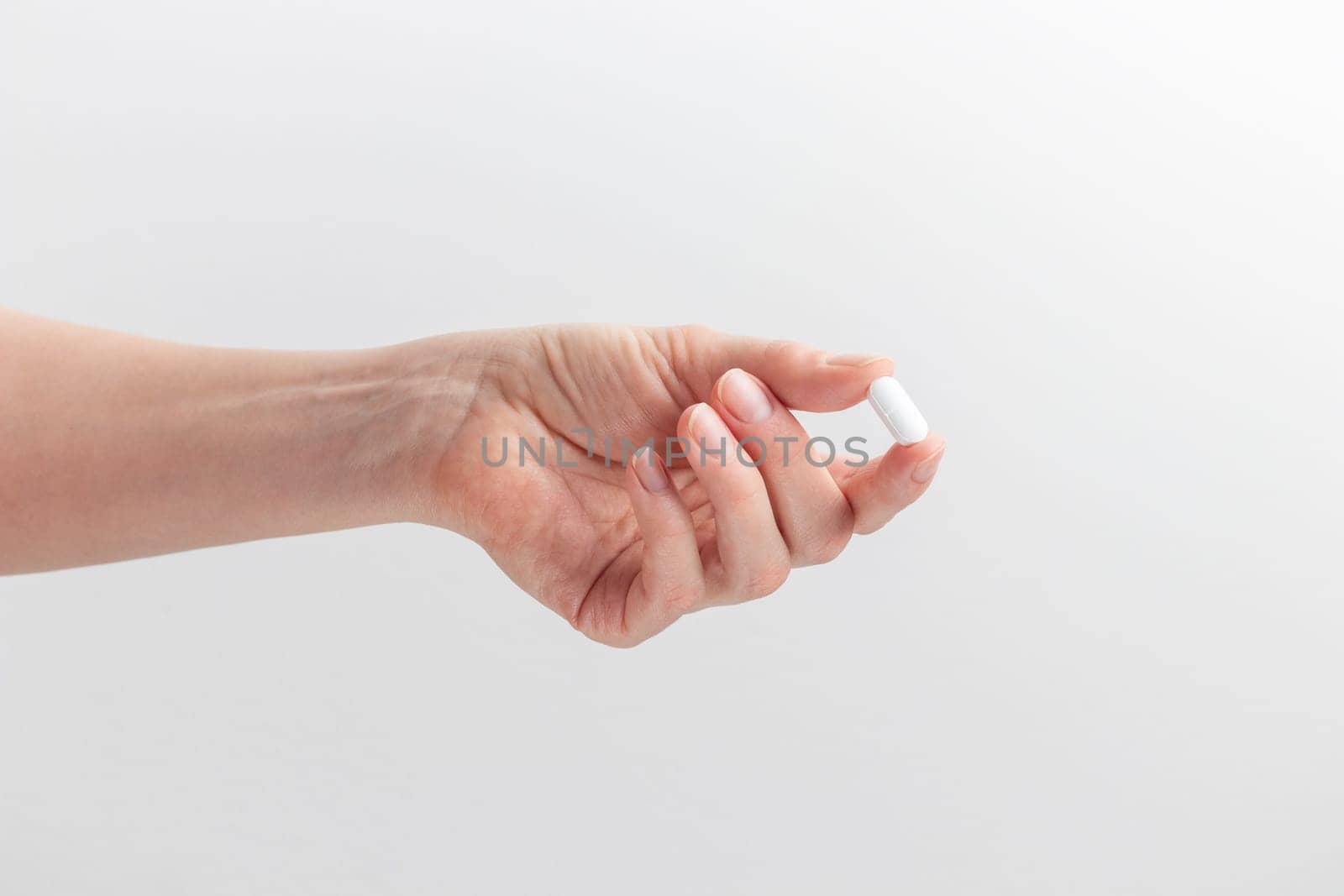 Female taking medicine, holding white pill and a glass of water on white background. Concept of health care, dietary supplements, treatment of depression and diseases. High-quality photo