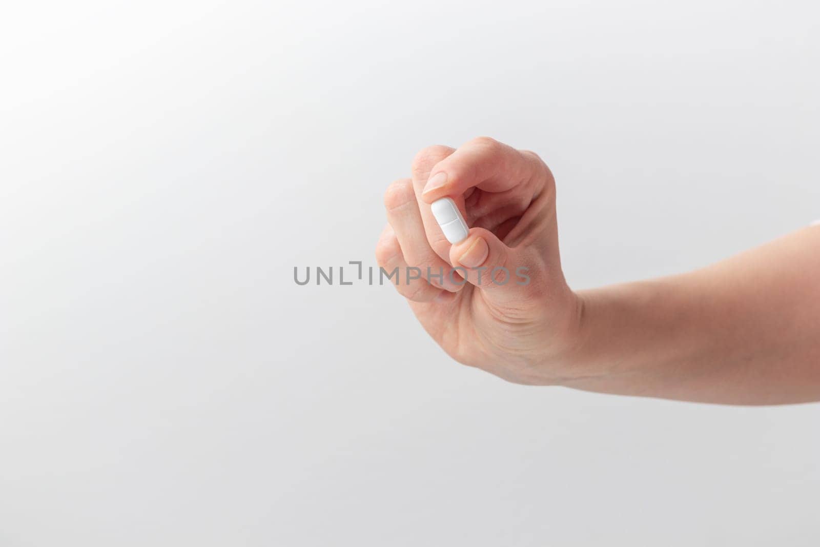 Female taking medicine, holding white pill and a glass of water on white background. Concept of health care, dietary supplements, treatment of depression and diseases. High-quality photo