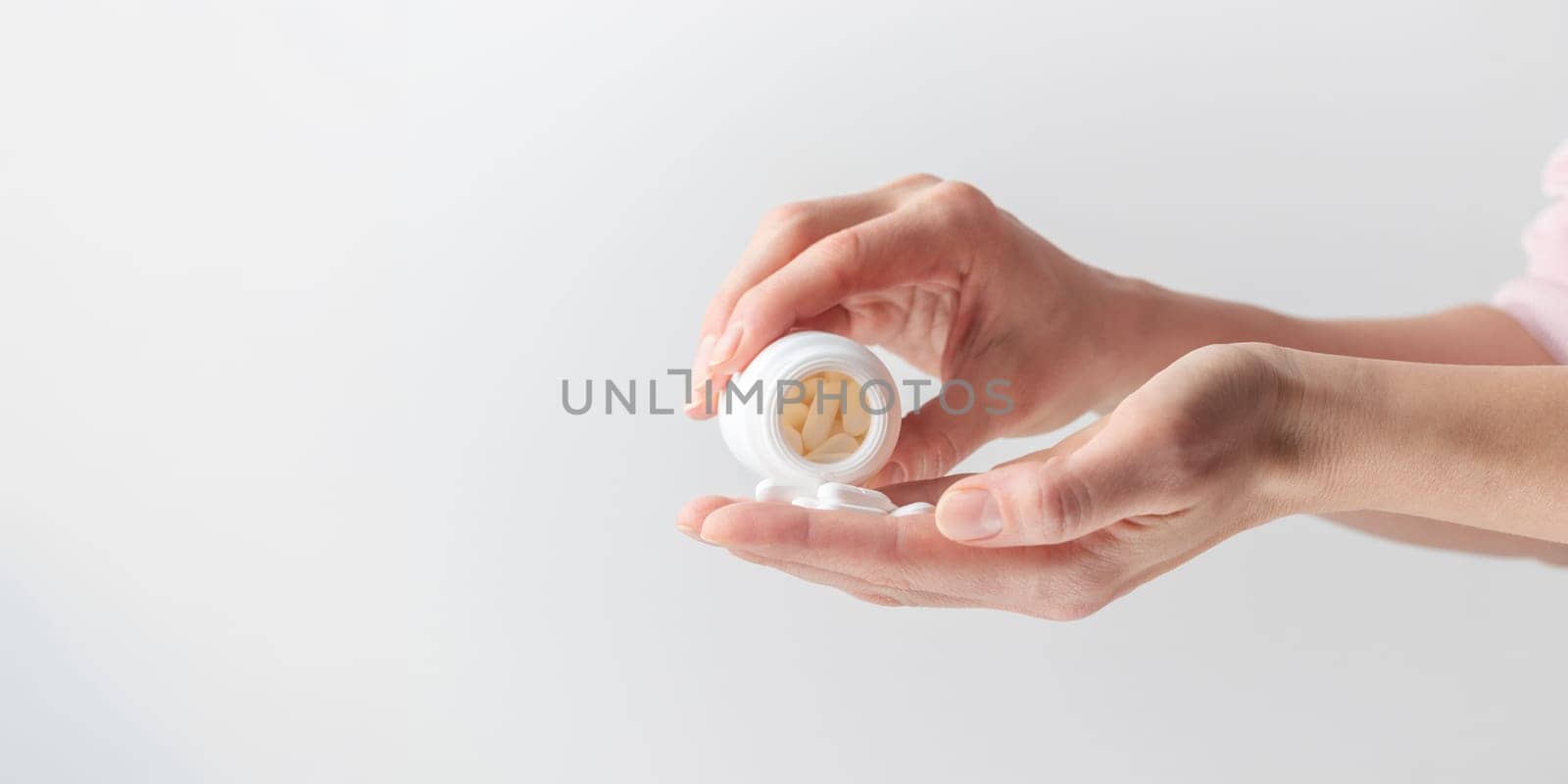 Female taking medicine, holding white pill and a glass of water on white background. Concept of health care, dietary supplements, treatment of depression and diseases. High-quality photo